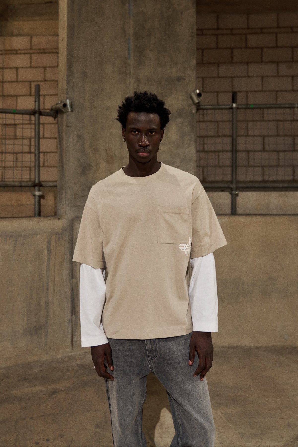 Model wearing the Double Layer Emblem Long Sleeve T-Shirt in Beige, front view