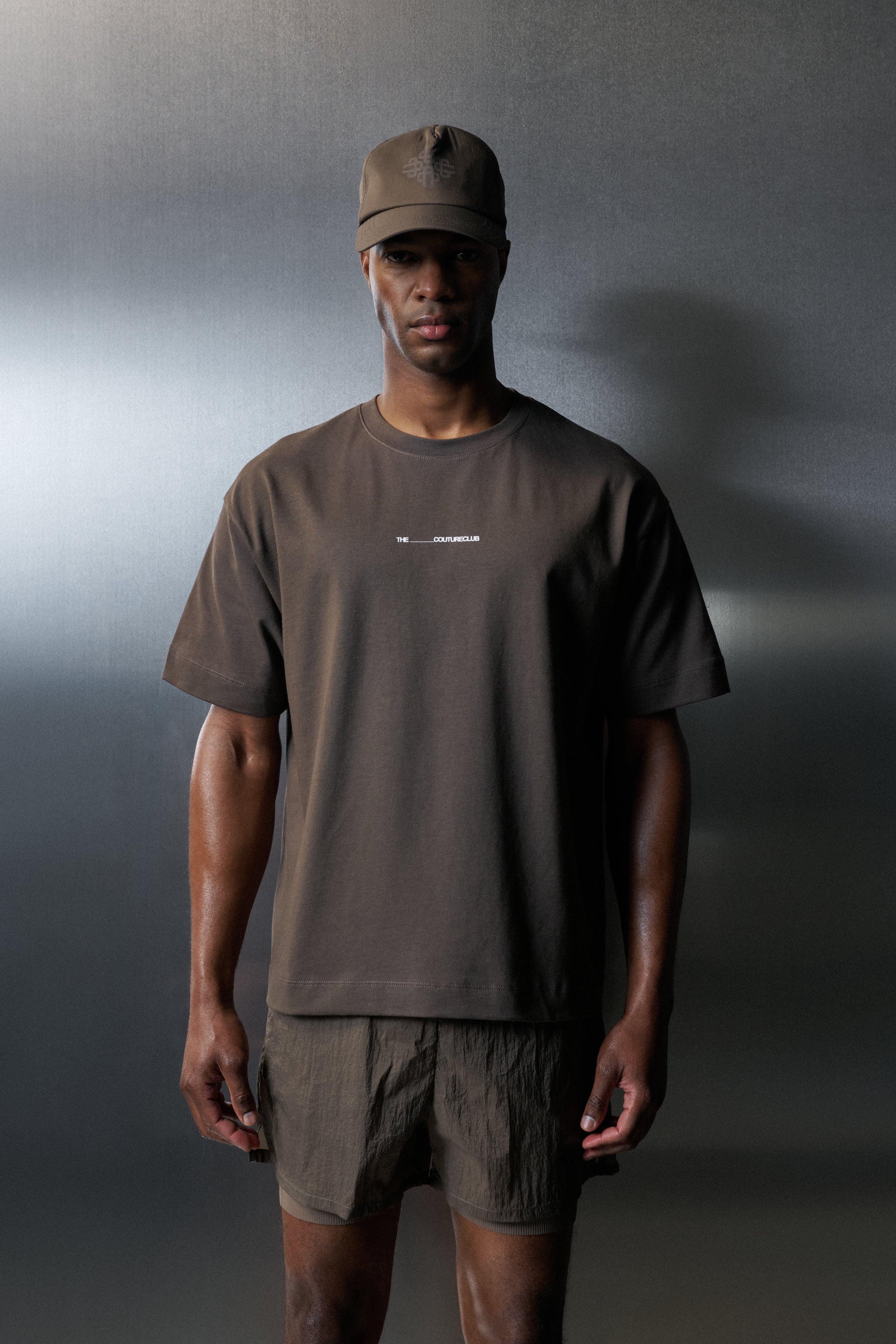 Person wearing a brown t-shirt and shorts set against a gradient background
