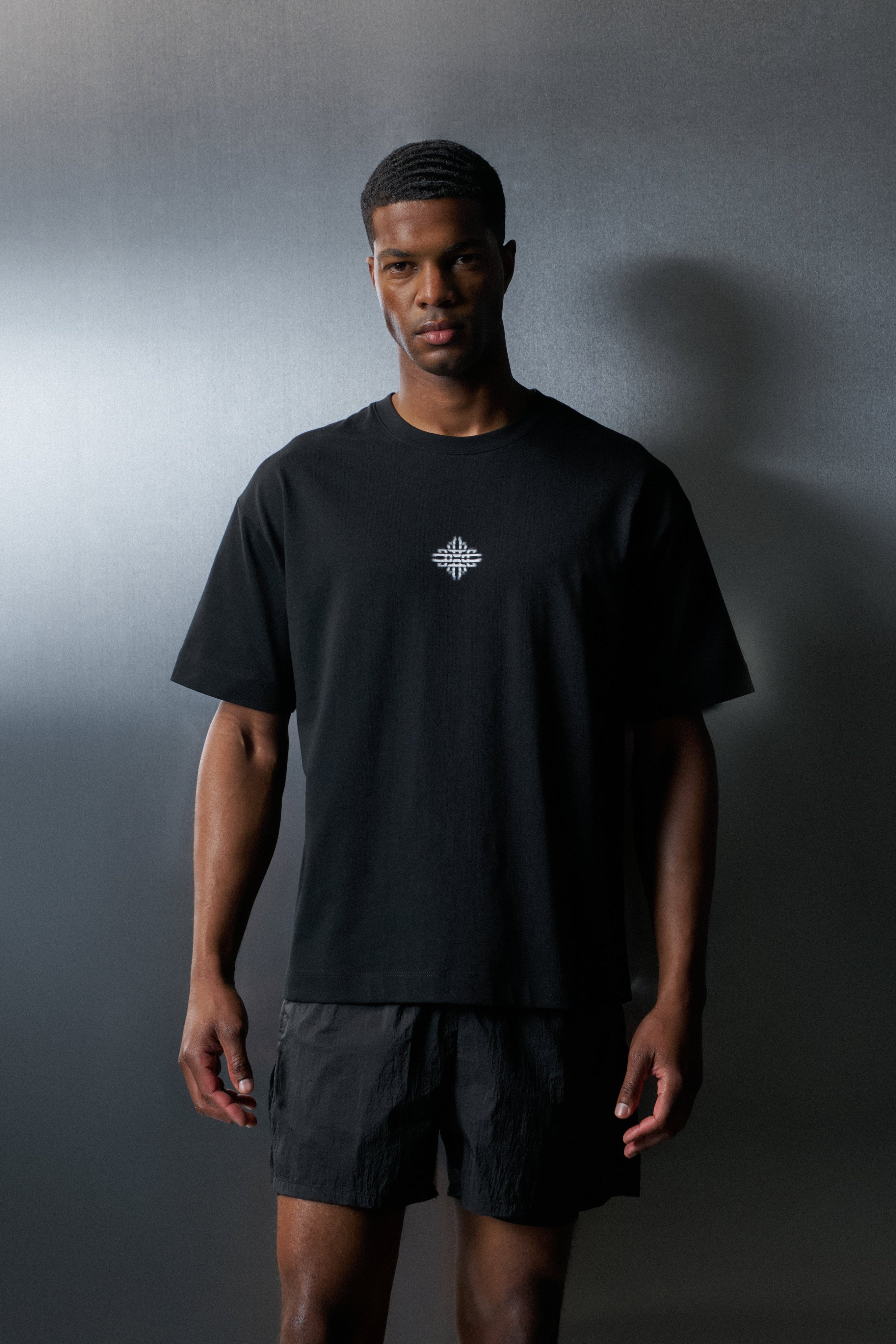 Man wearing a black t-shirt with a logo against a dark background