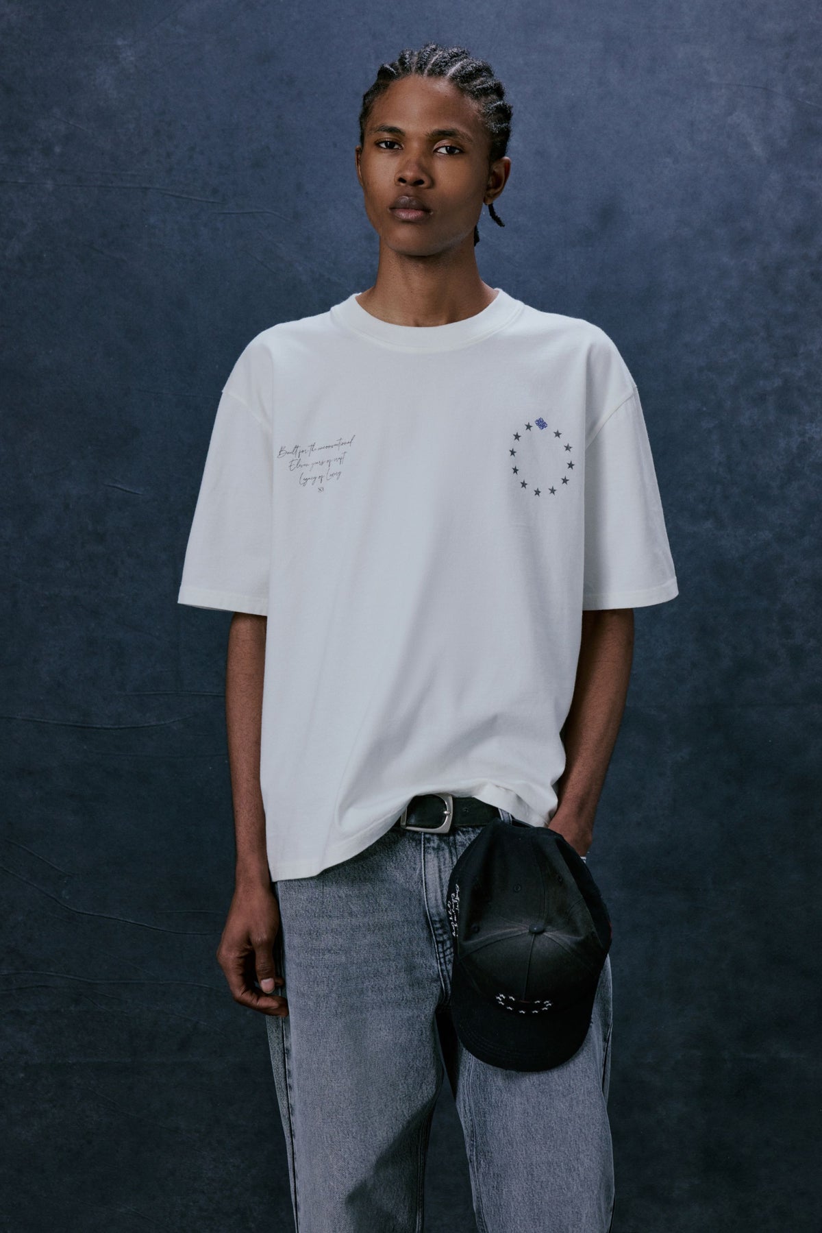 Men's Legacy Graphic T-Shirt in White – model front view holding a cap