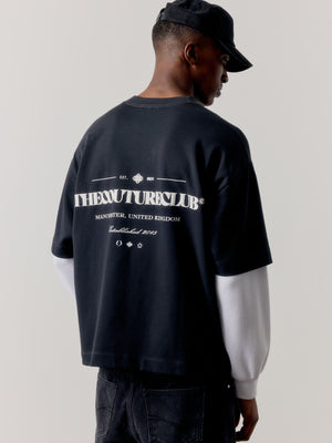 Person wearing a black oversized sweatshirt with branded text on the back against a plain background