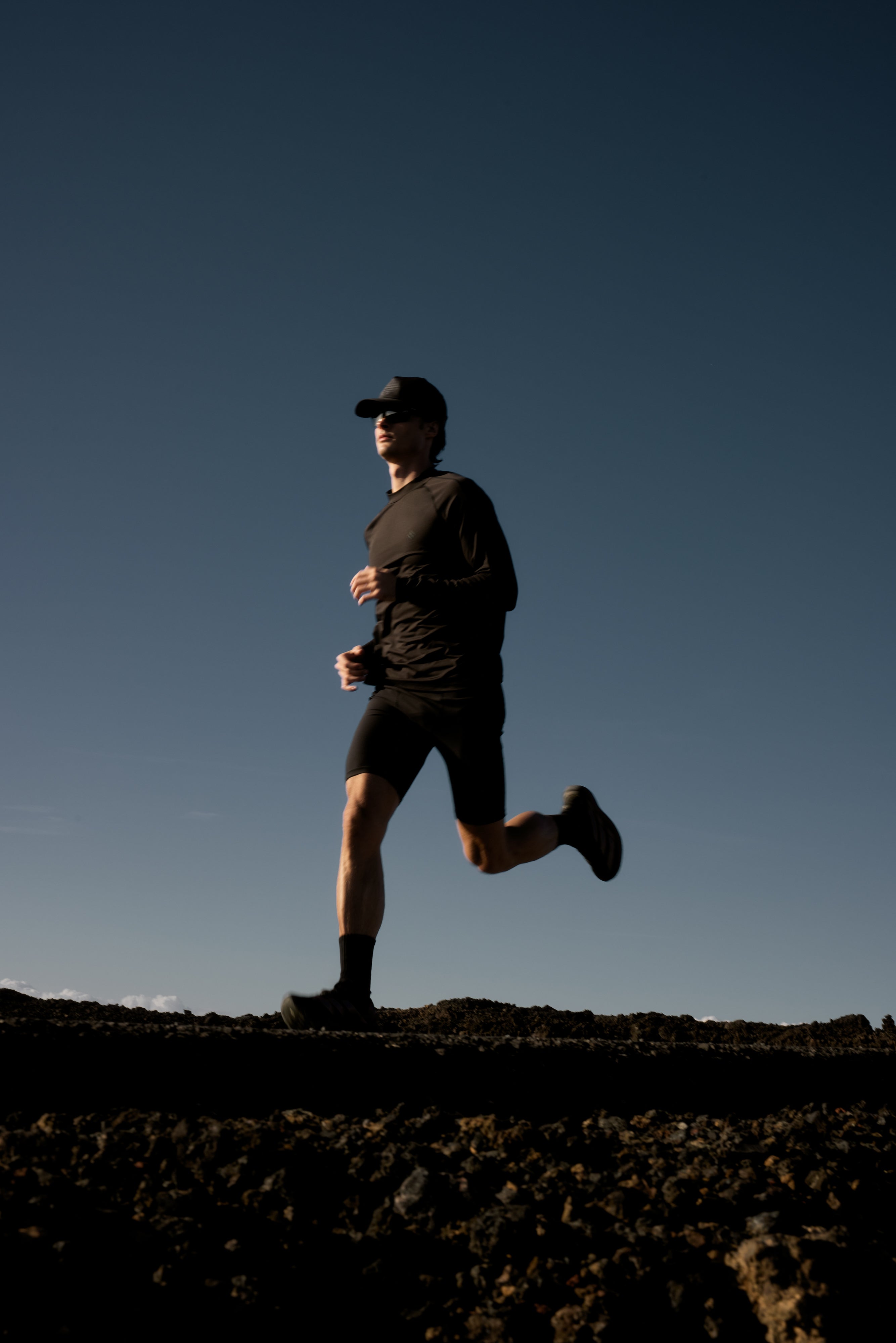 Person running on a dirt path with a clear blue sky