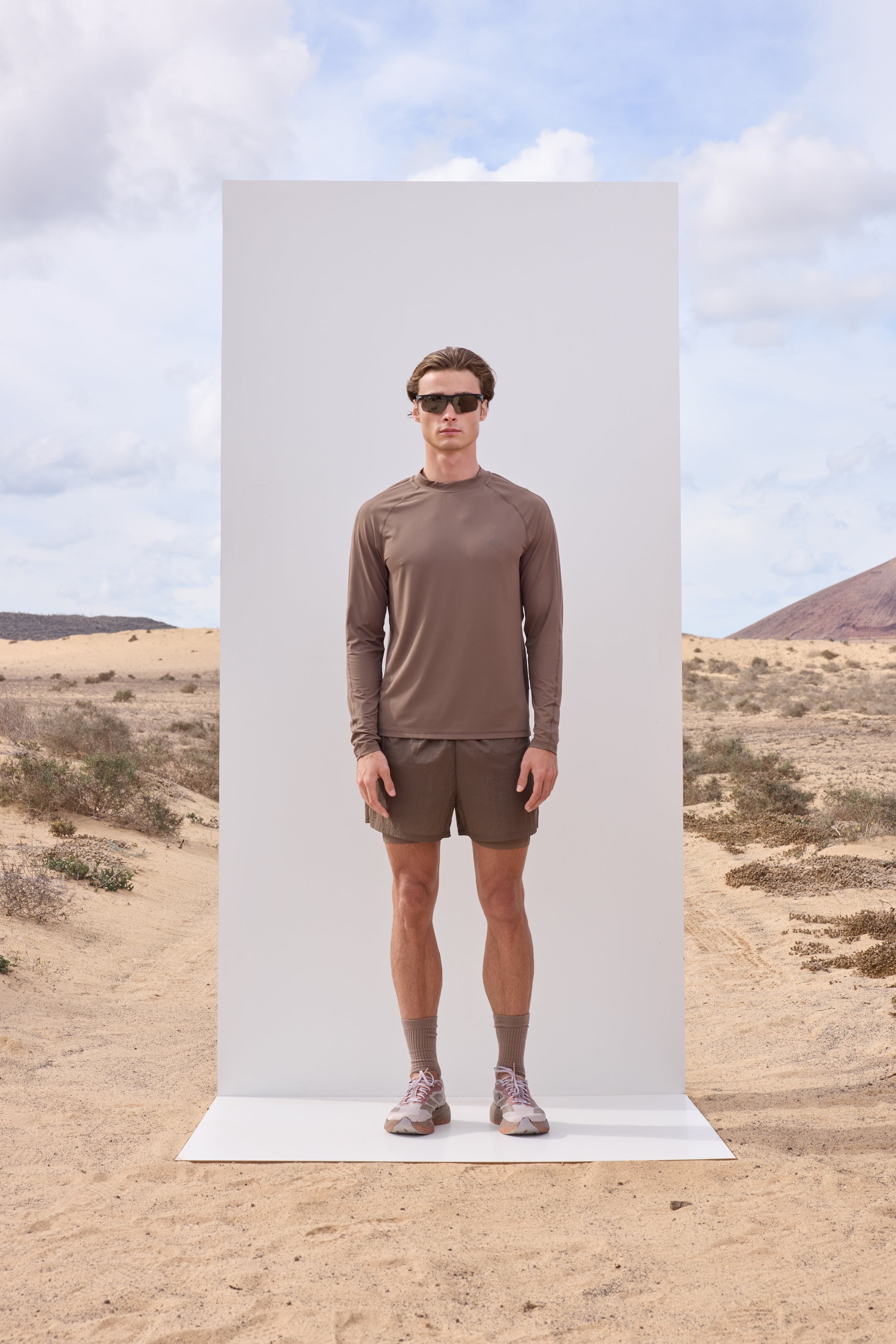 Man standing against a white backdrop in a desert landscape