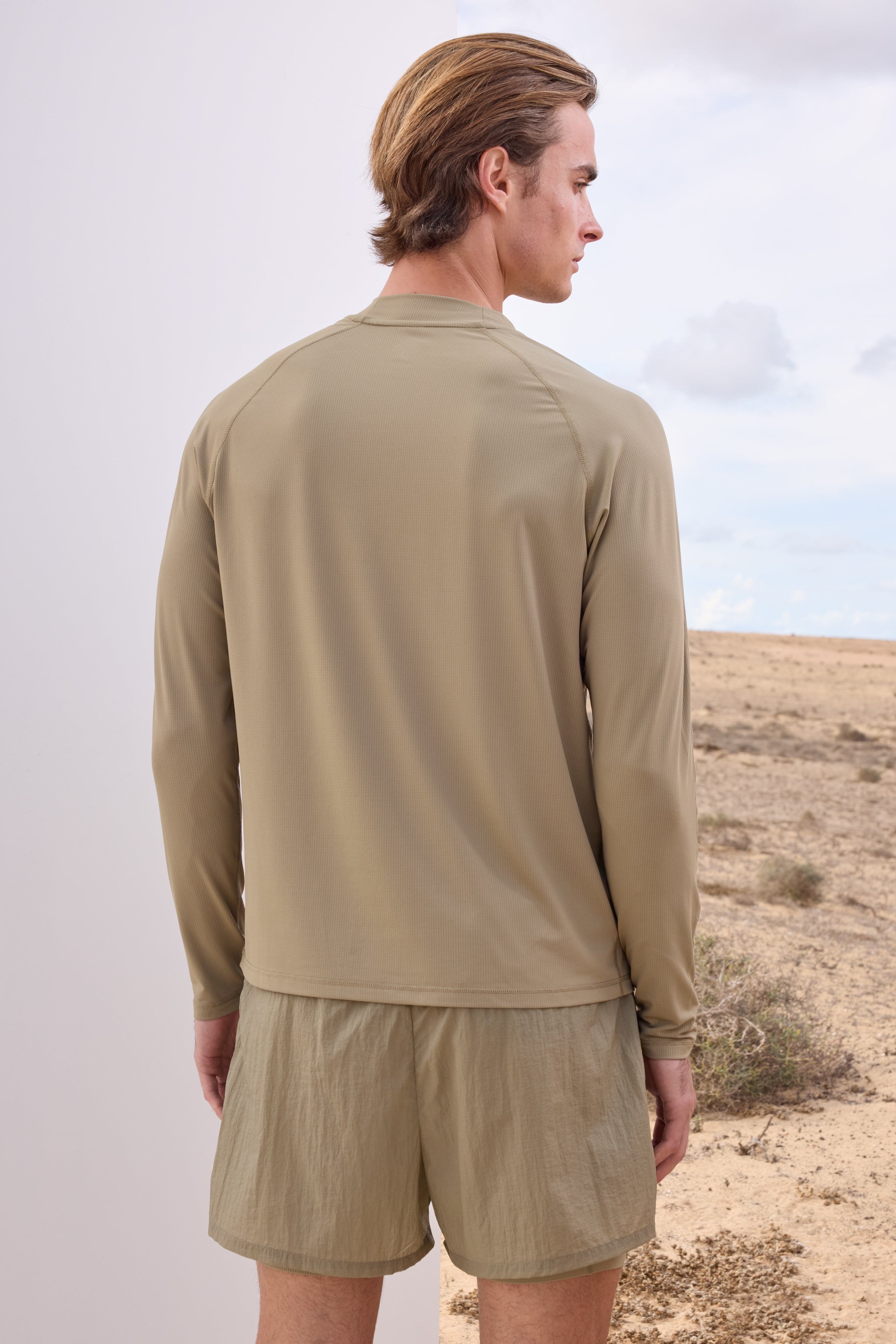 Man wearing a khaki long-sleeve t-shirt and shorts in a desert setting