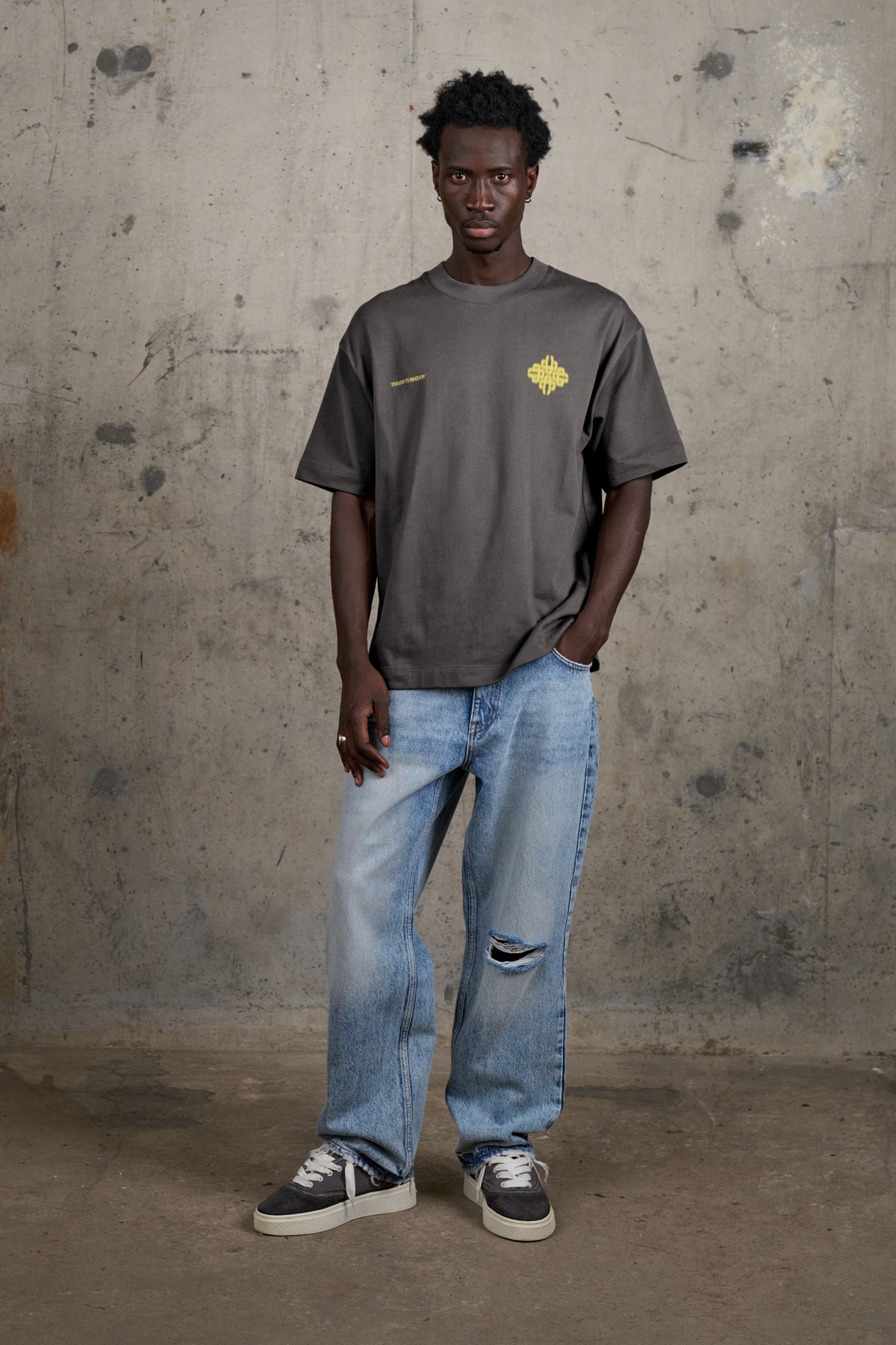 Model wearing the Motion Blurred Emblem T-Shirt in Charcoal/Yellow, full-length front view