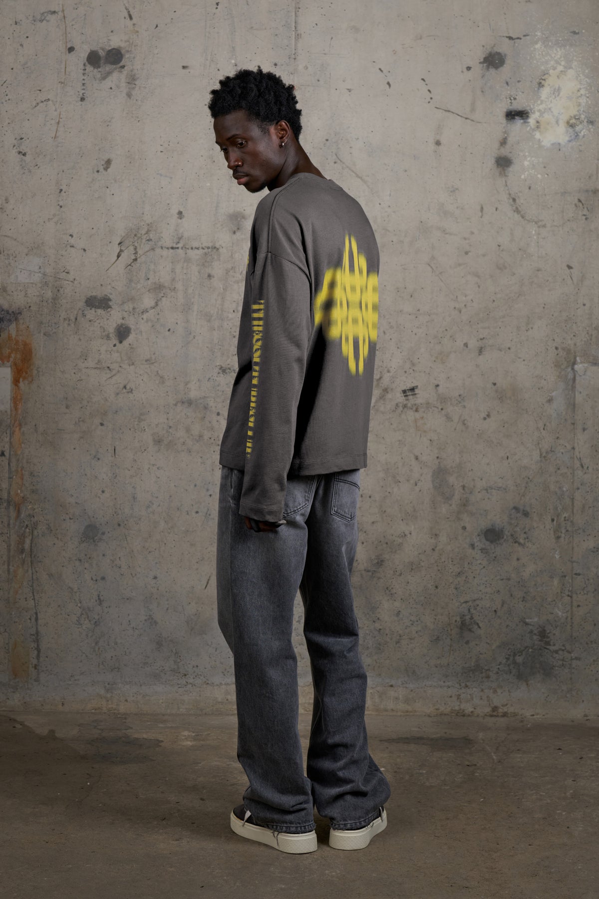 Model wearing the Motion Blurred Long Sleeve T-Shirt in Charcoal/Yellow, full-length side view