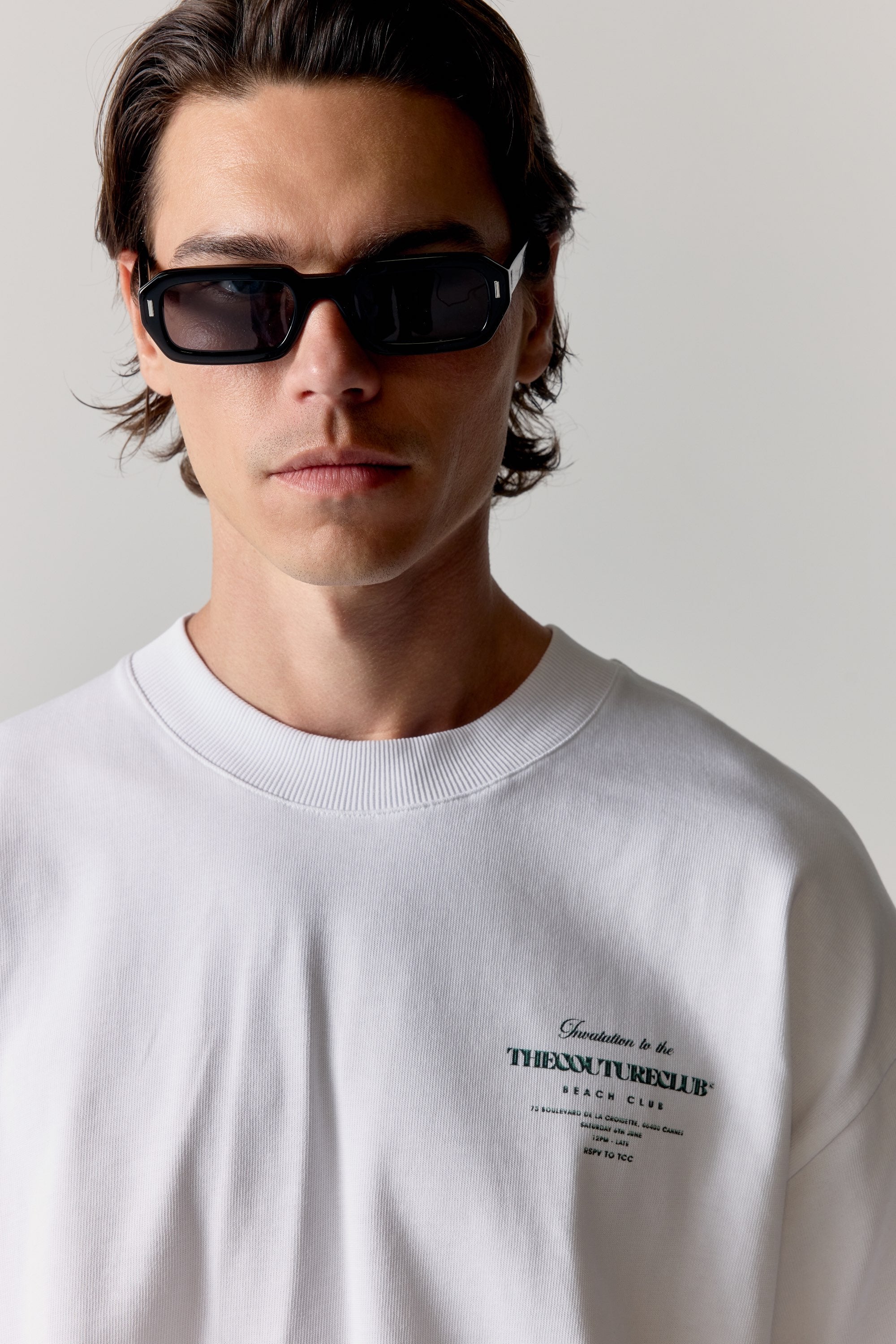 Person wearing a white t-shirt with green text on a plain background