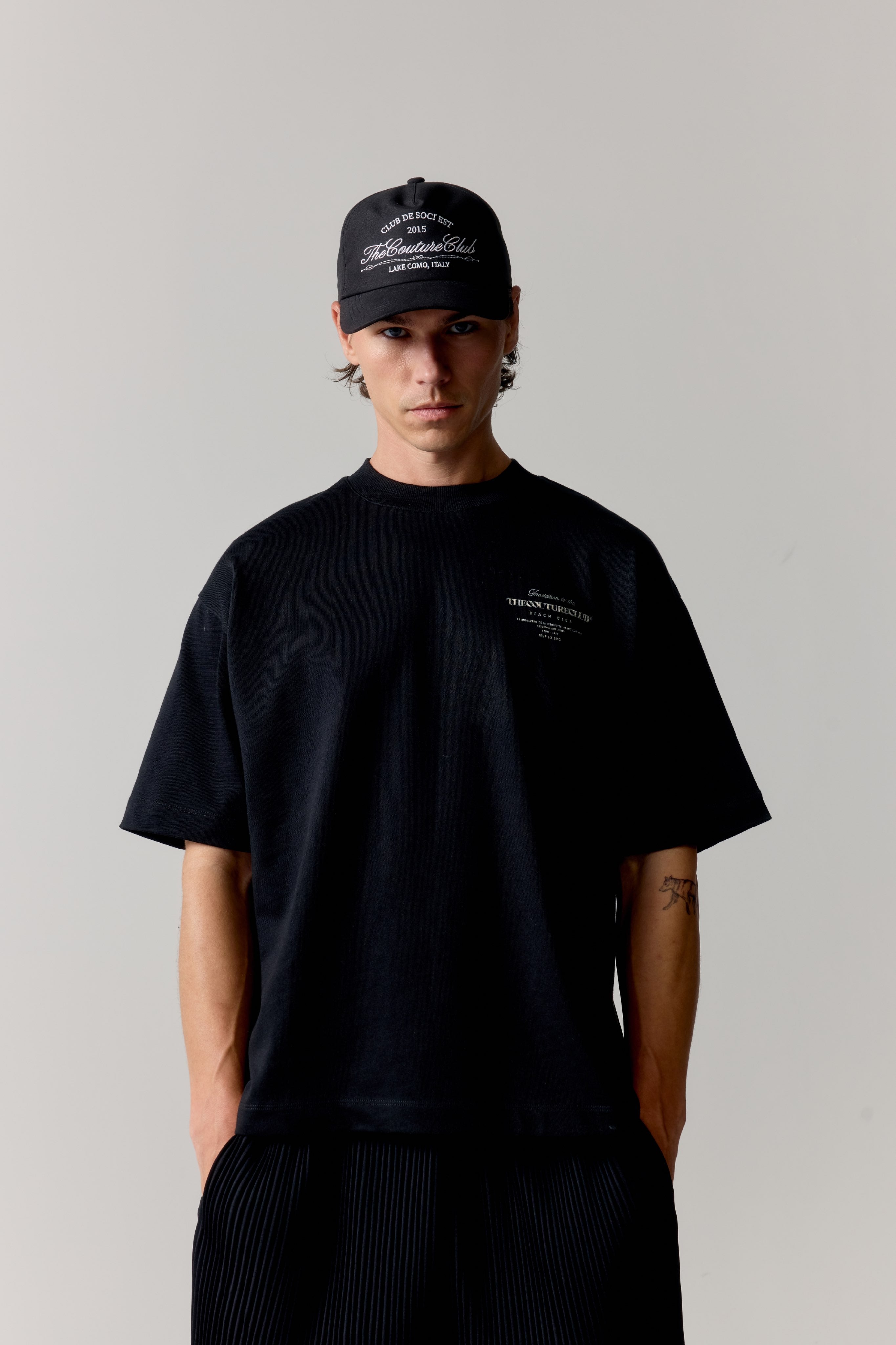 Person wearing a black t-shirt and cap with text on a plain background