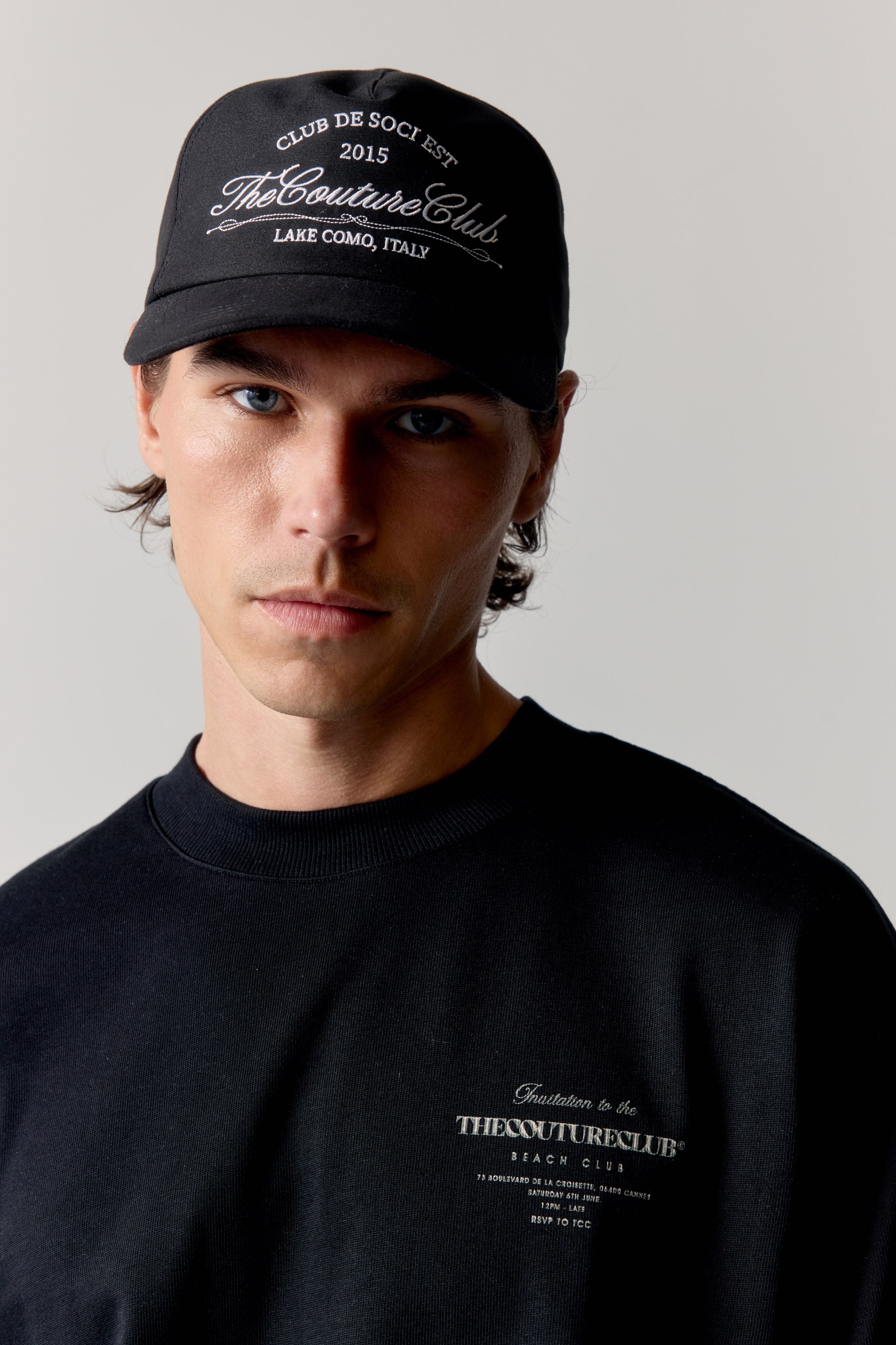 Man wearing a black cap and t-shirt with text on a light background