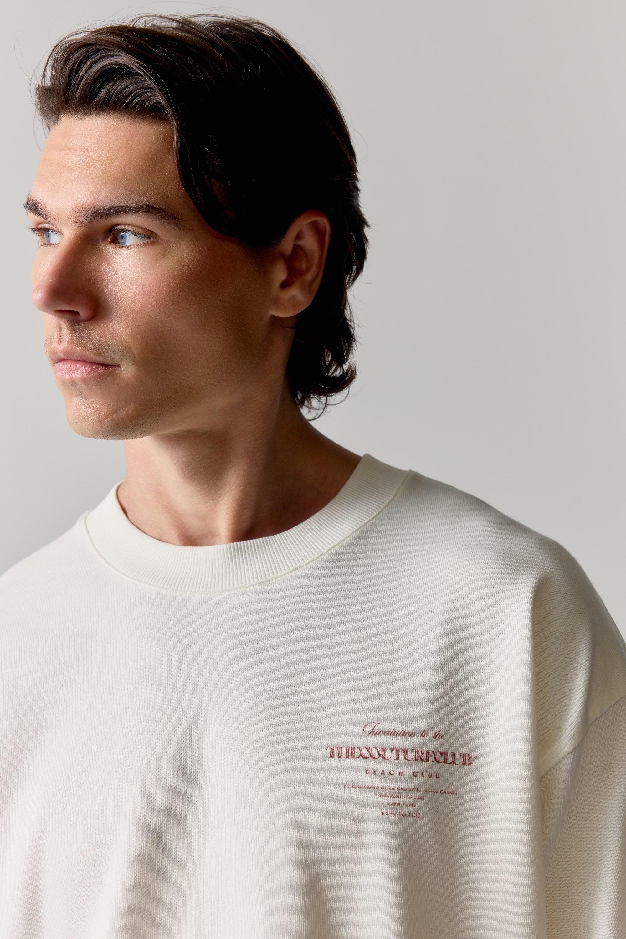 Man wearing a white t-shirt with pink text on a plain background