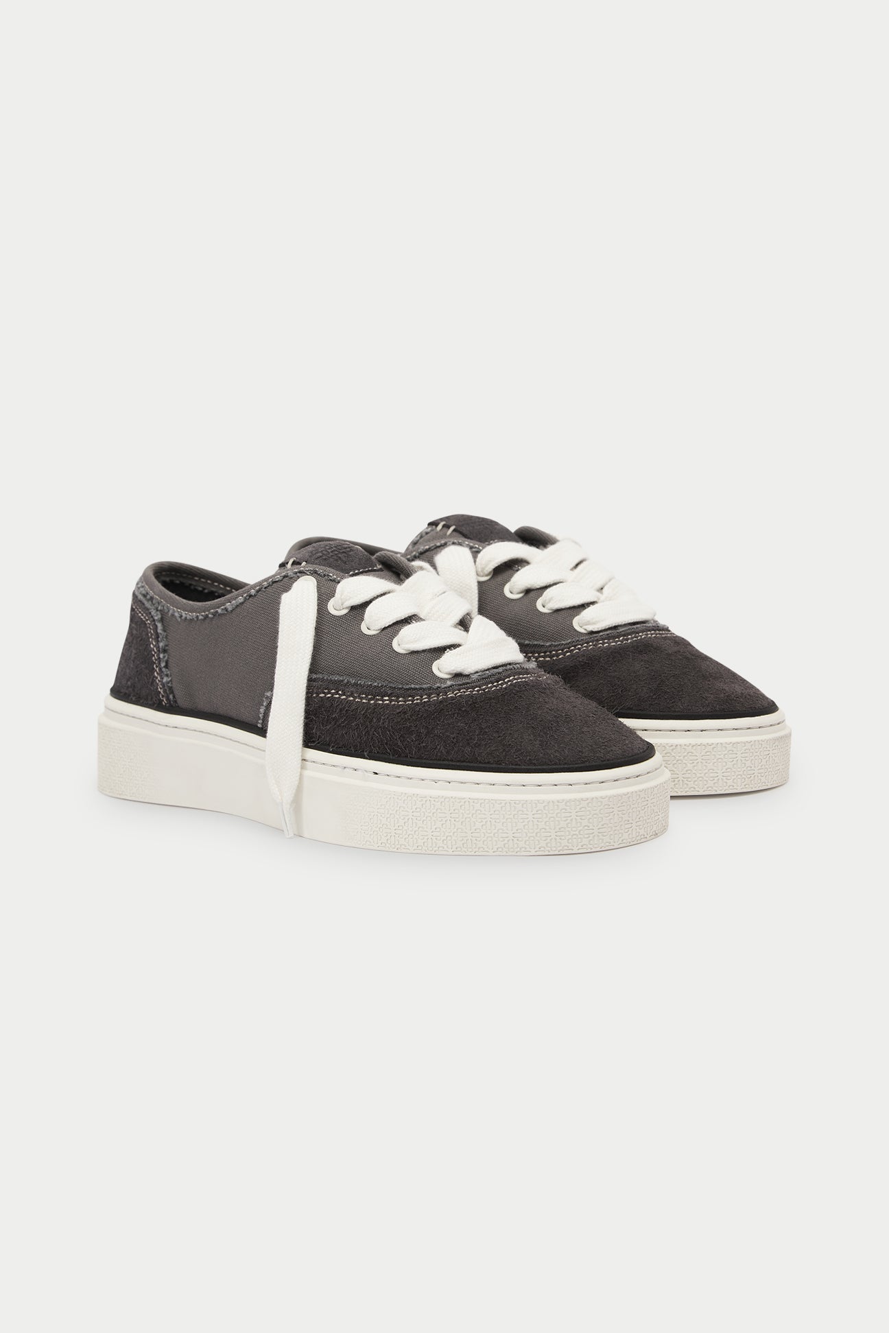 Pair of dark grey sneakers with white soles on a white background
