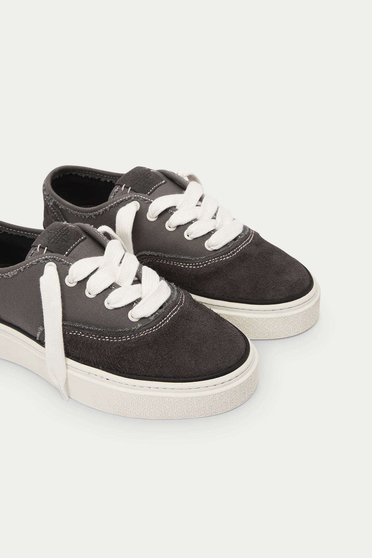 Pair of dark grey sneakers with white laces on a white background