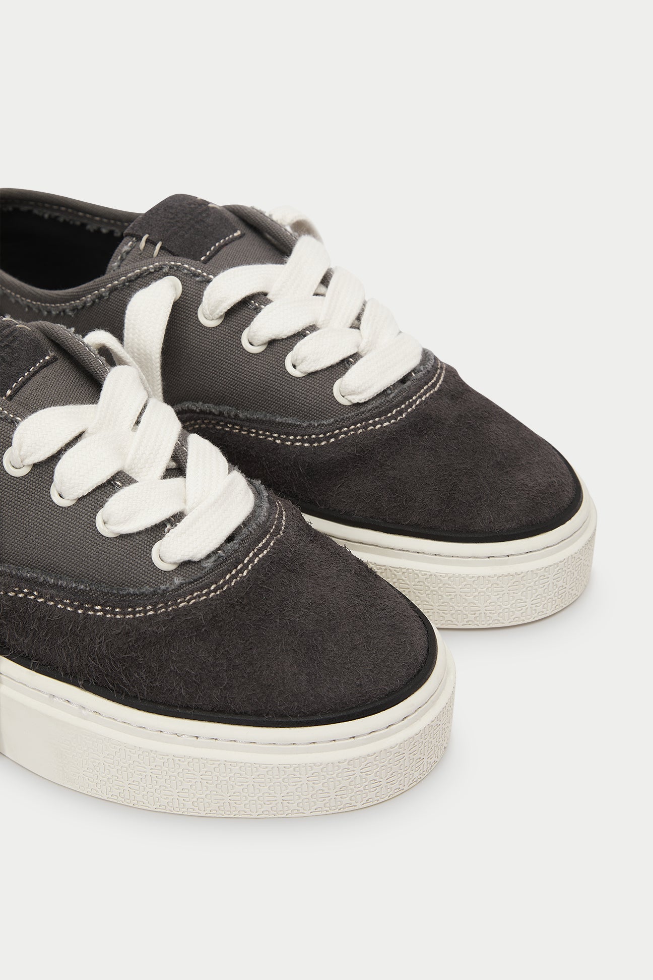 Pair of dark grey sneakers with white laces on a white background