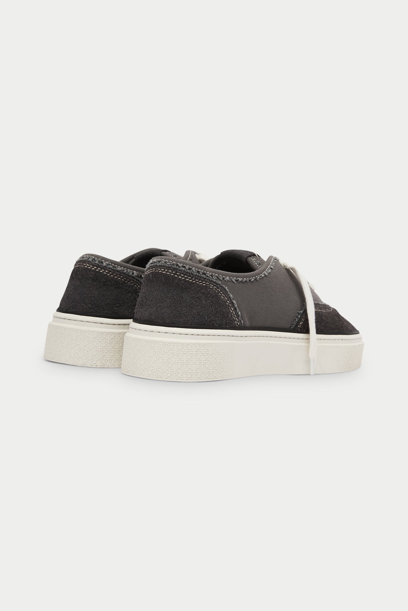 Pair of dark grey sneakers with white laces on a white background