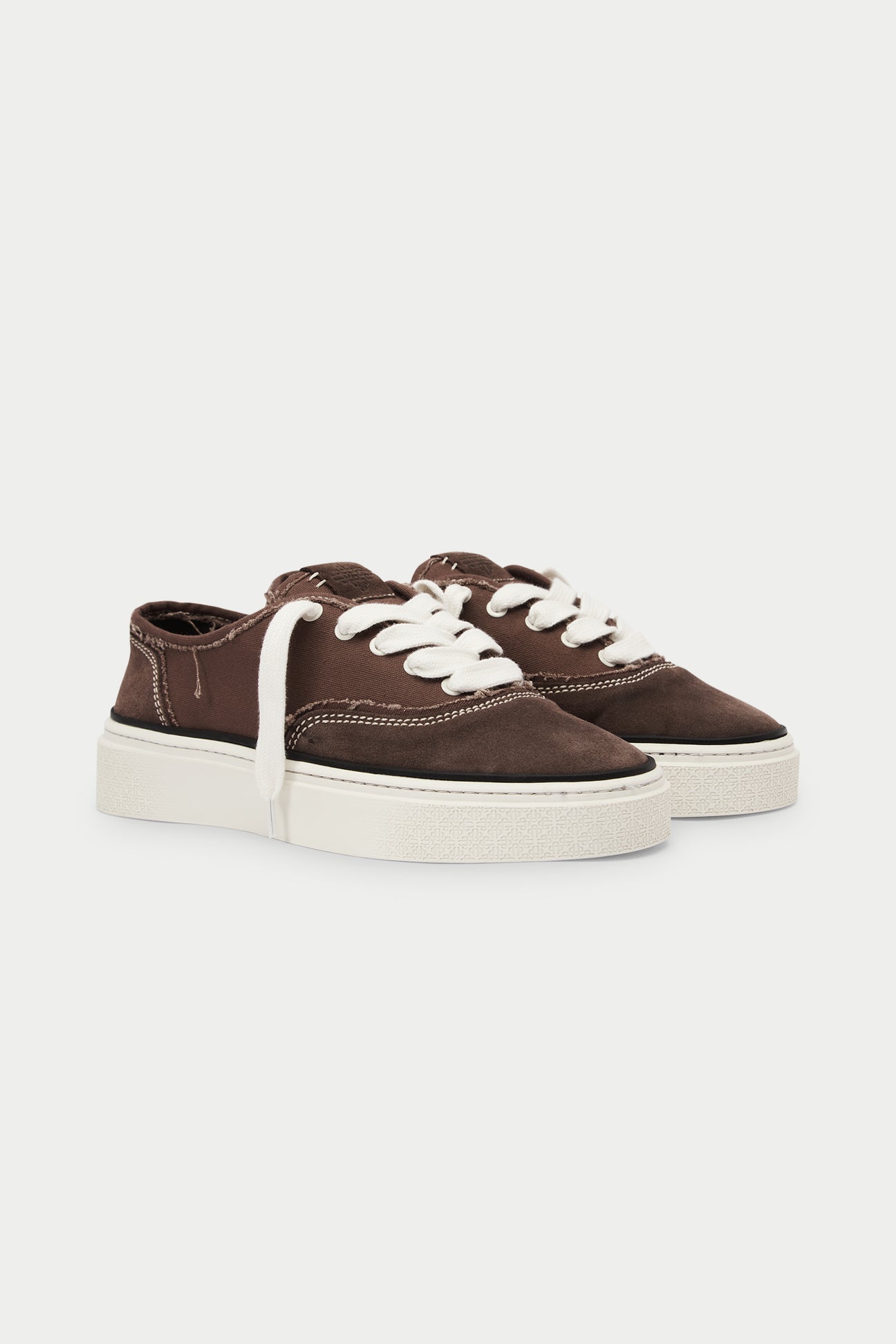 Pair of brown sneakers with white soles on a white background