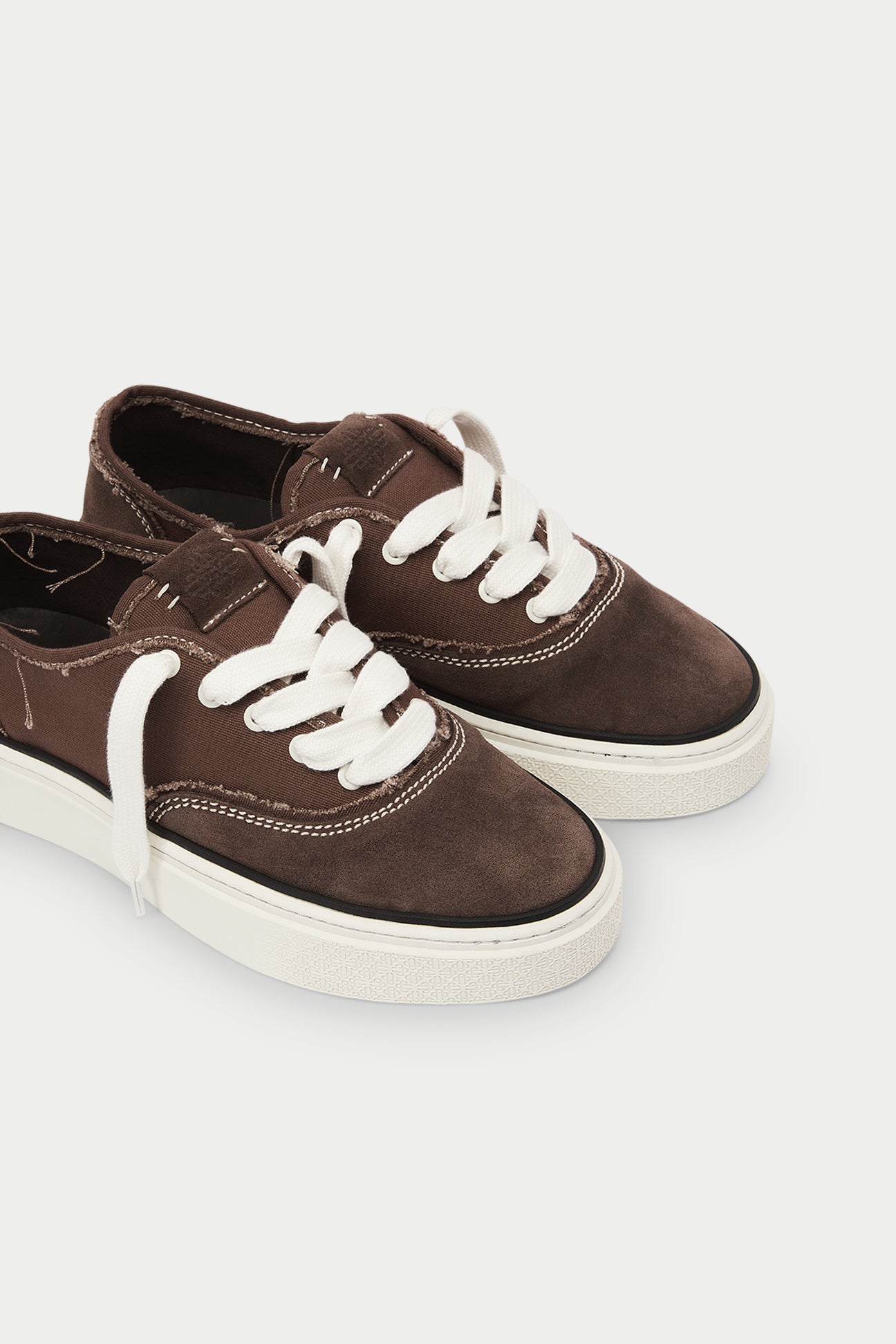 Pair of brown sneakers with white laces on a white background