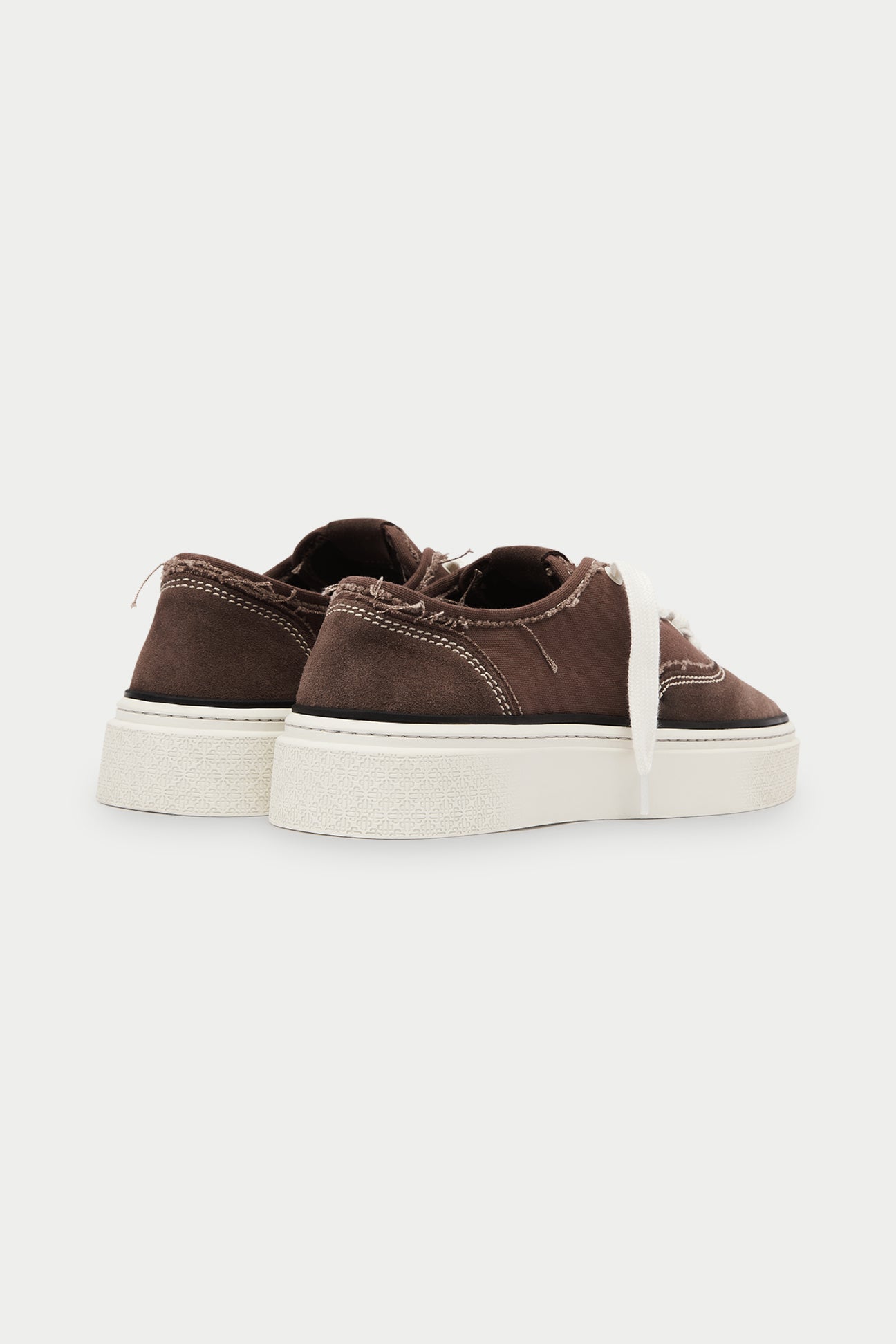Pair of brown sneakers with white laces and white soles on a white background.
