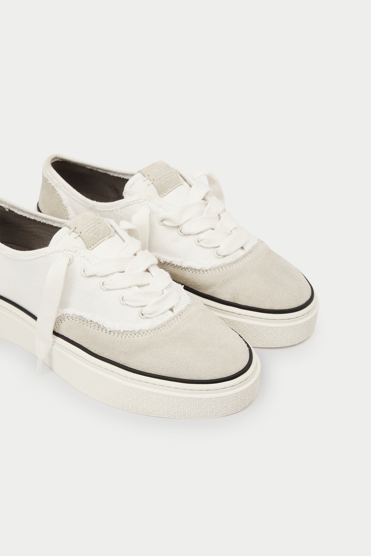 Pair of white and beige sneakers and black accents on a white background.