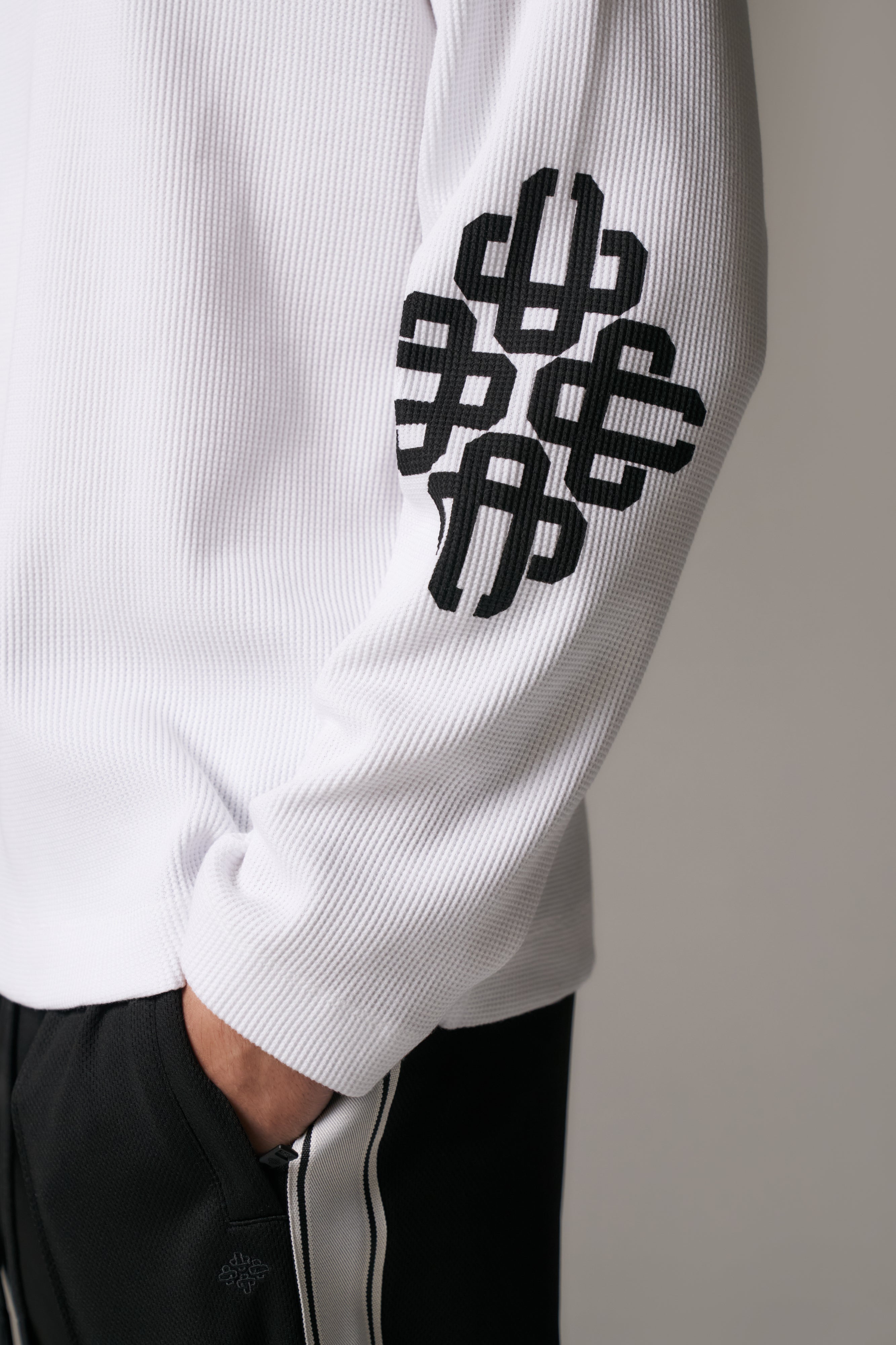 White long sleeved t-shirt with black geometric patterns on a plain background