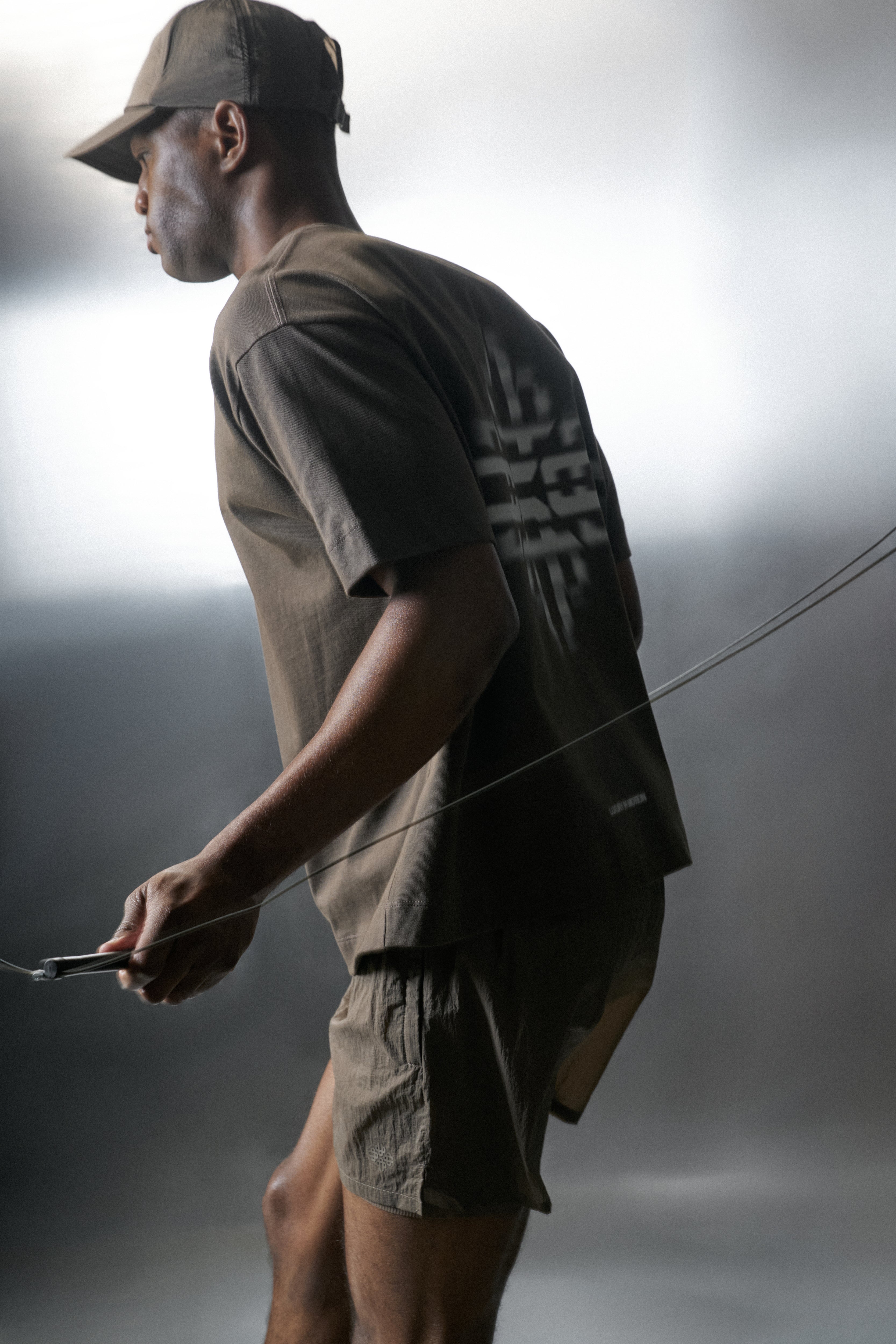 Man in athletic wear holding a rope against a grey background