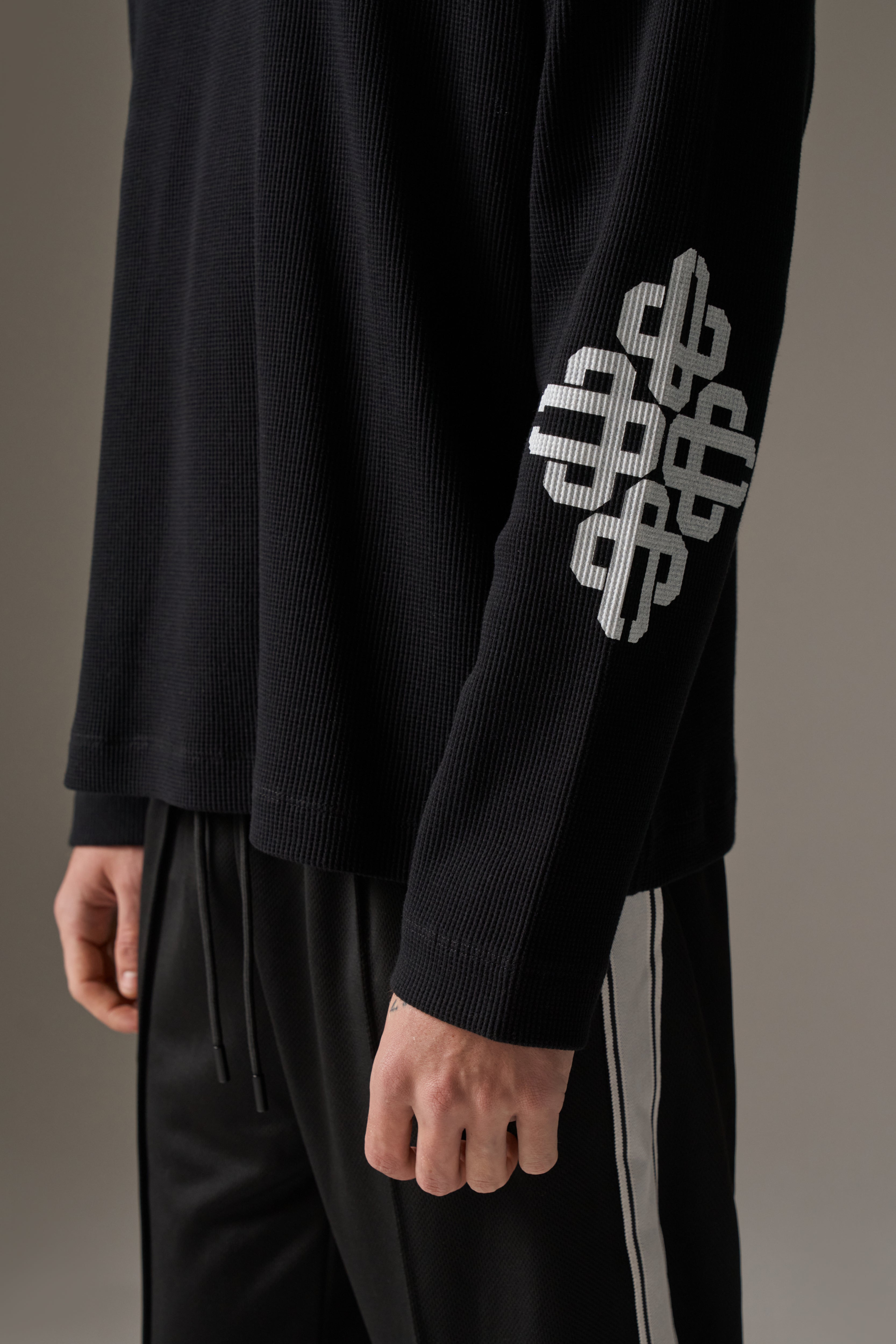 Black long-sleeve t-shirt with a white geometric design on a grey background