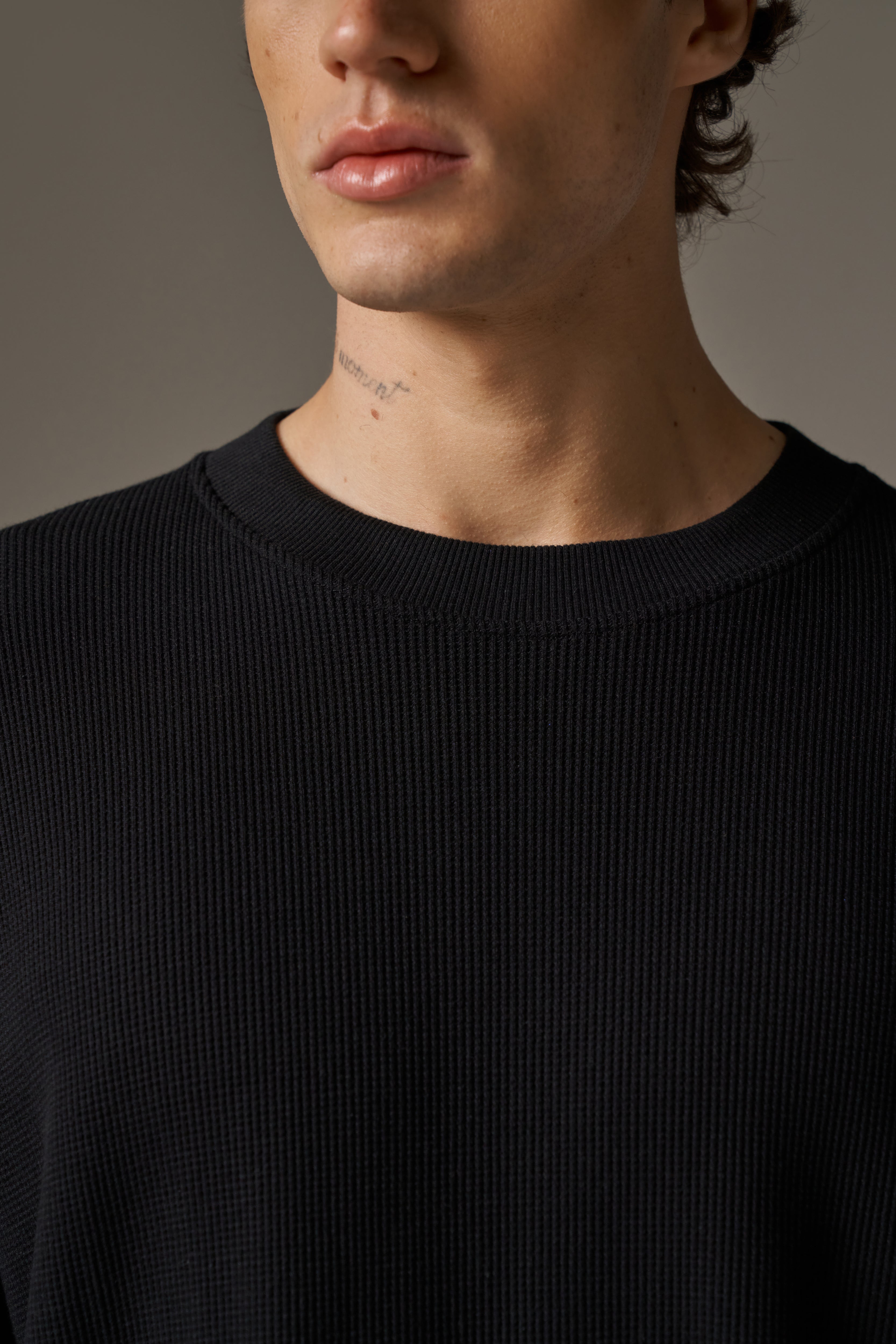 Close-up of a person wearing a black t-shirt against a neutral background