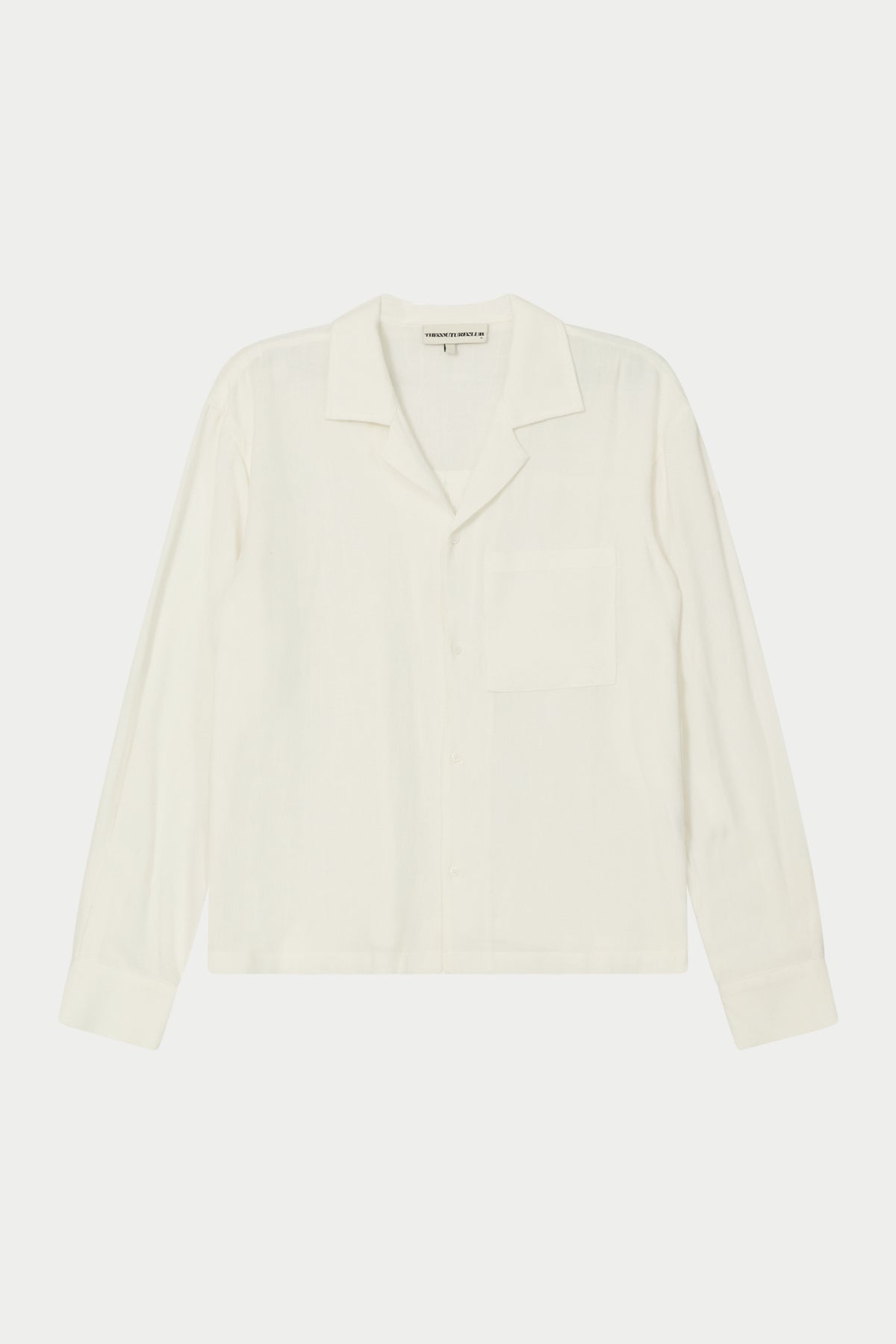 A white, long-sleeved, relaxed fit woven shirt with a revere collar and an oversized chest pocket, displayed on a plain background.