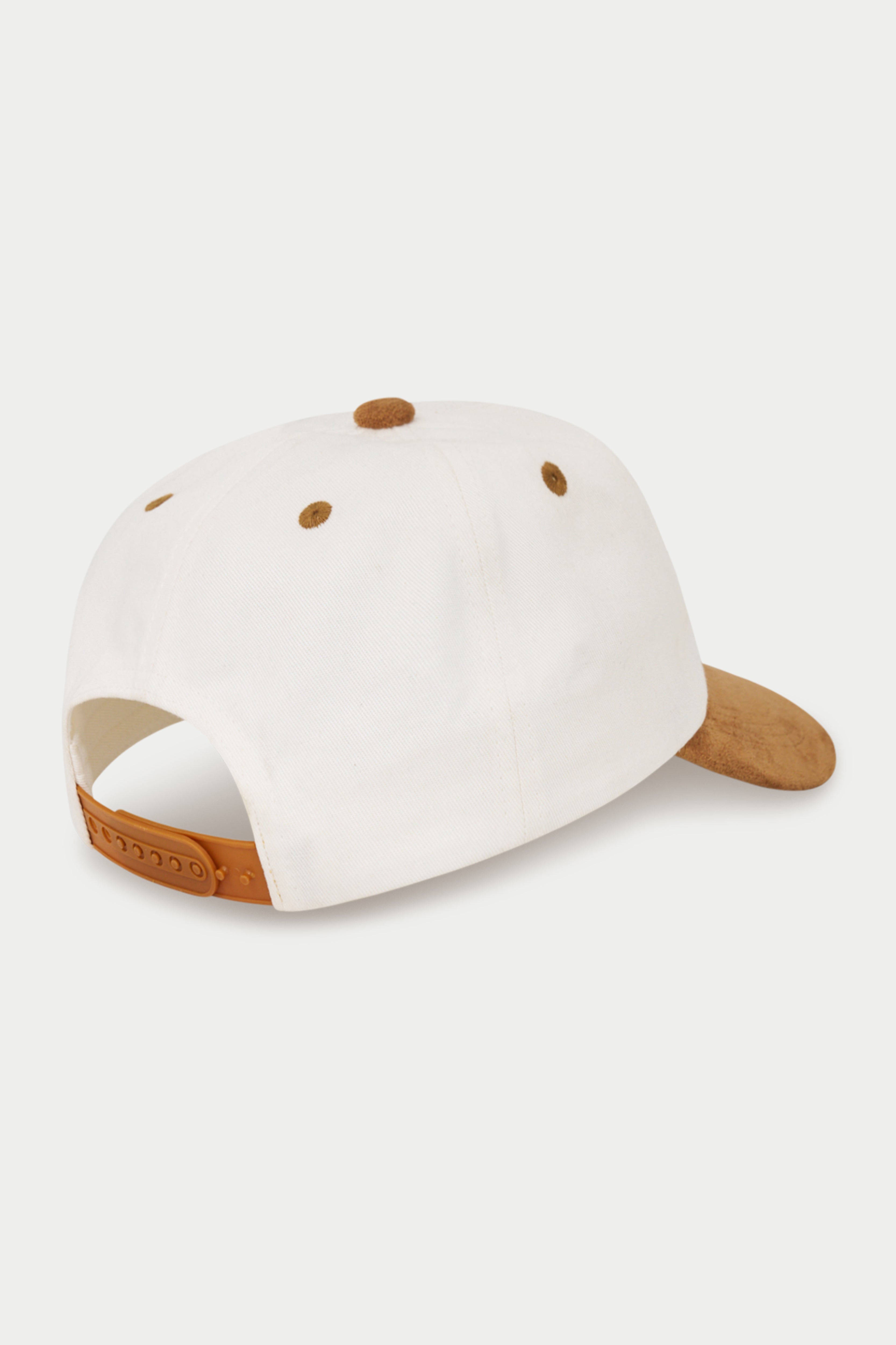 A white baseball cap shown from a rear three-quarter angle, featuring light brown leather accents on the visor and adjustable strap, with matching brown ventilation eyelets.