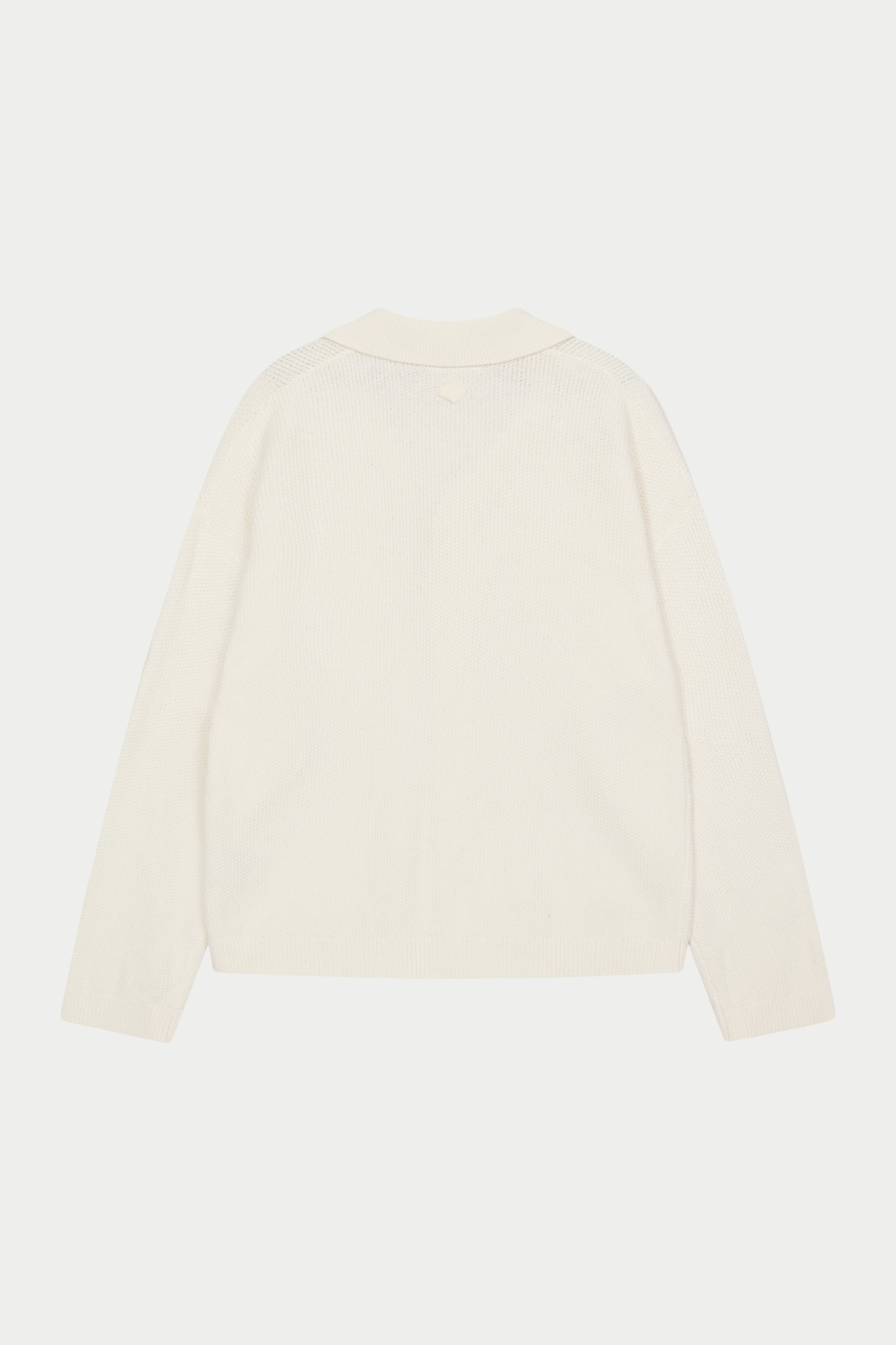 A long-sleeved off white shirt with a ribbed revere collar and crochet knit fabric against a white background.