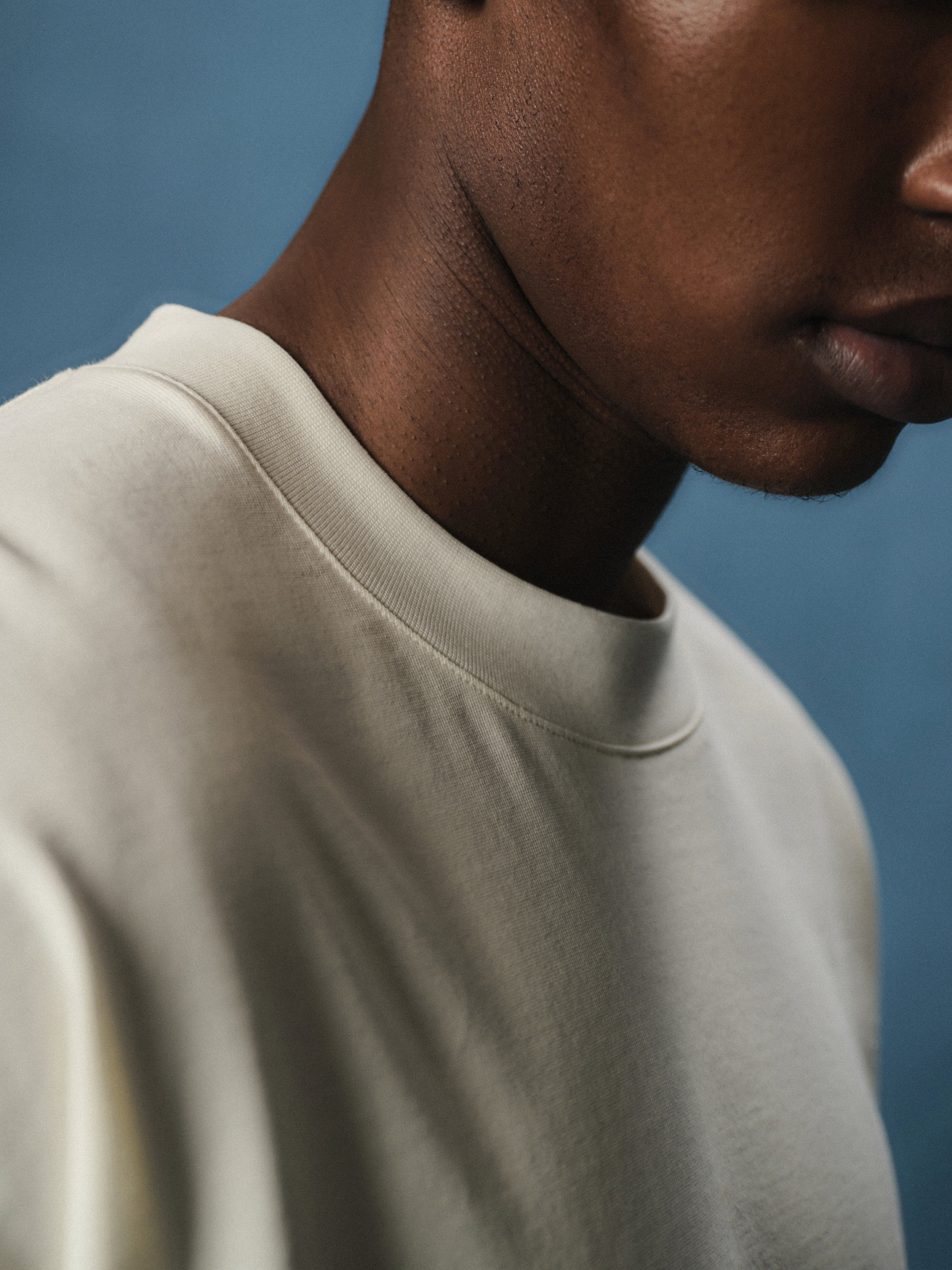 Close up view of neckline of a man wearing an off white t-shirt