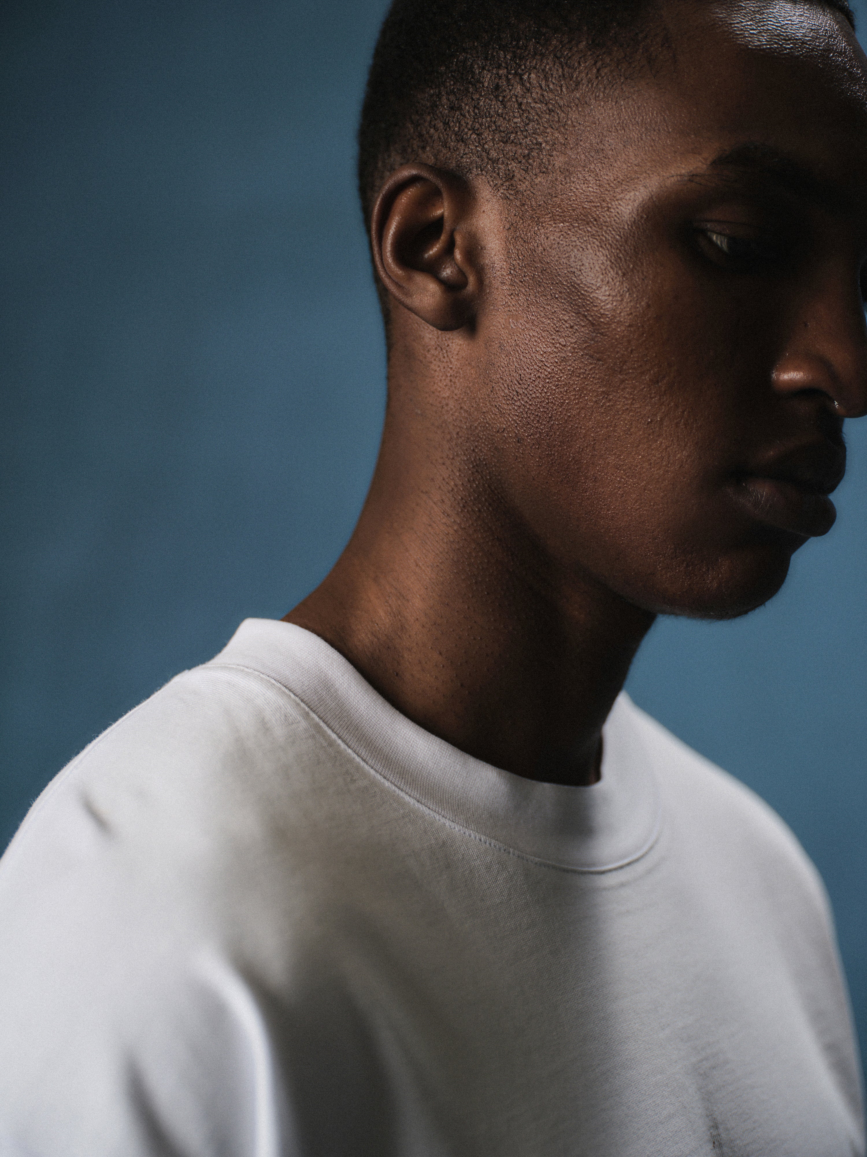 Man wearing a white long sleeved t-shirt against a blue background