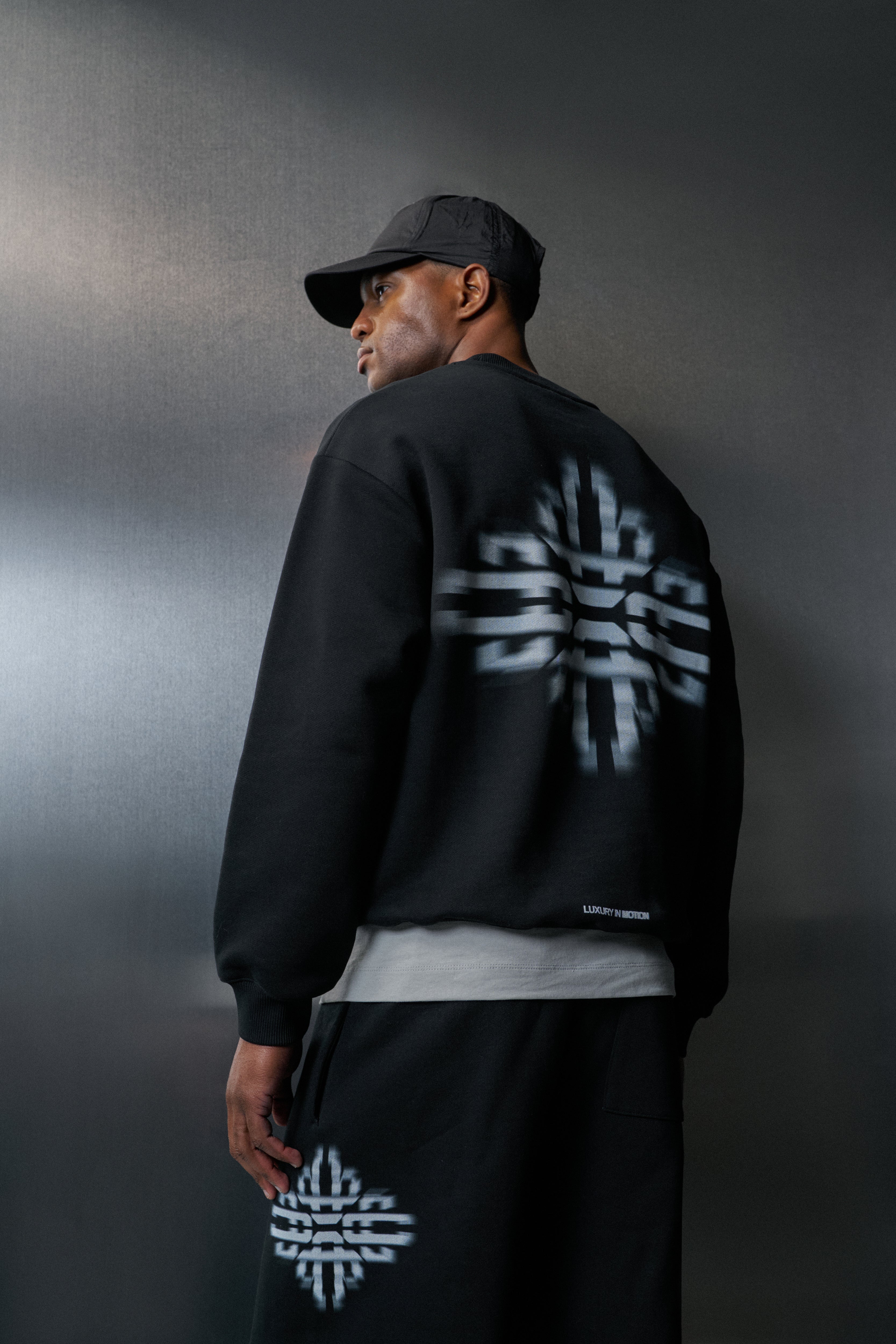 Person wearing a black sweatshirt with white logo on a dark background