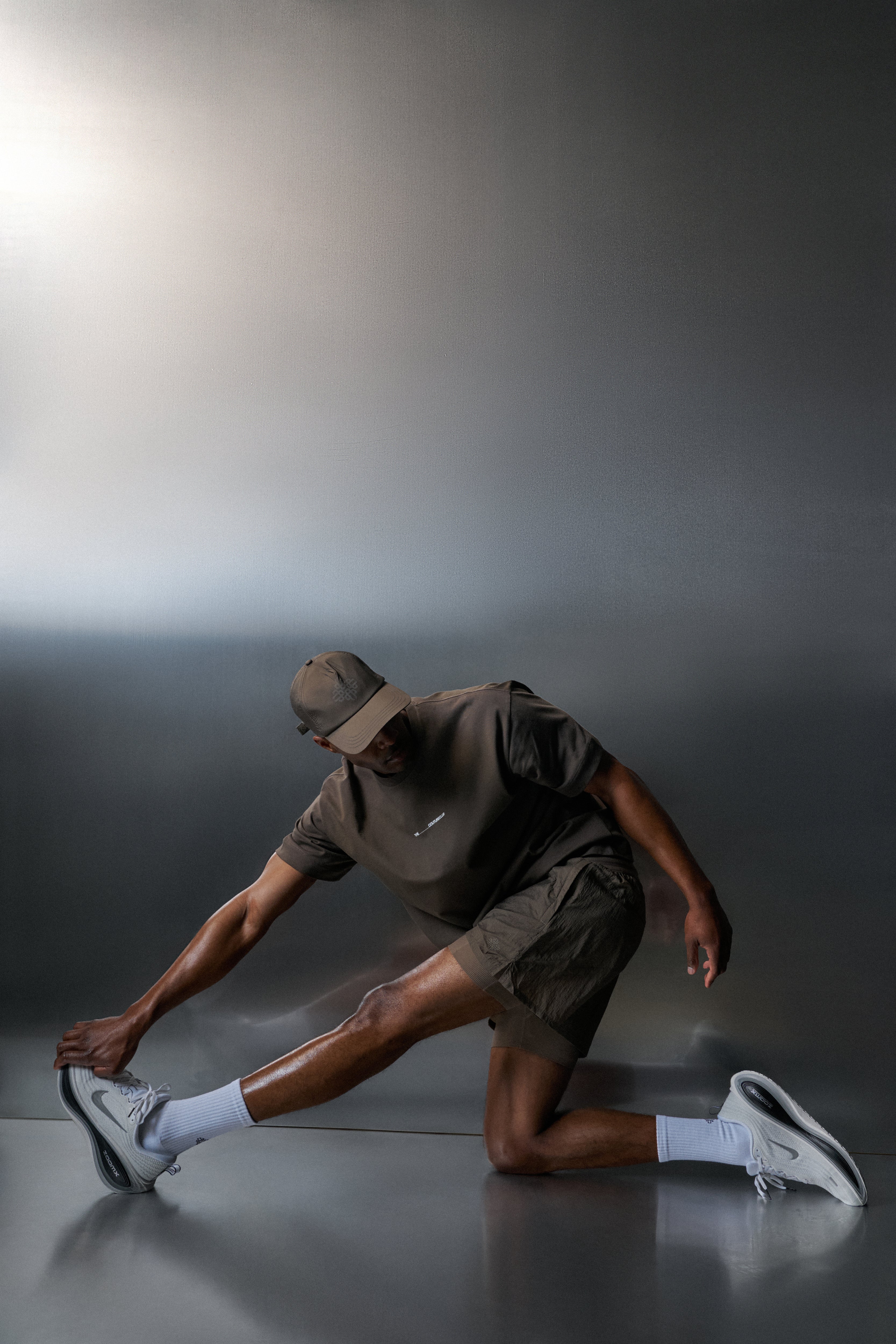 Person in brown outfit stretching on a reflective surface with a dark background