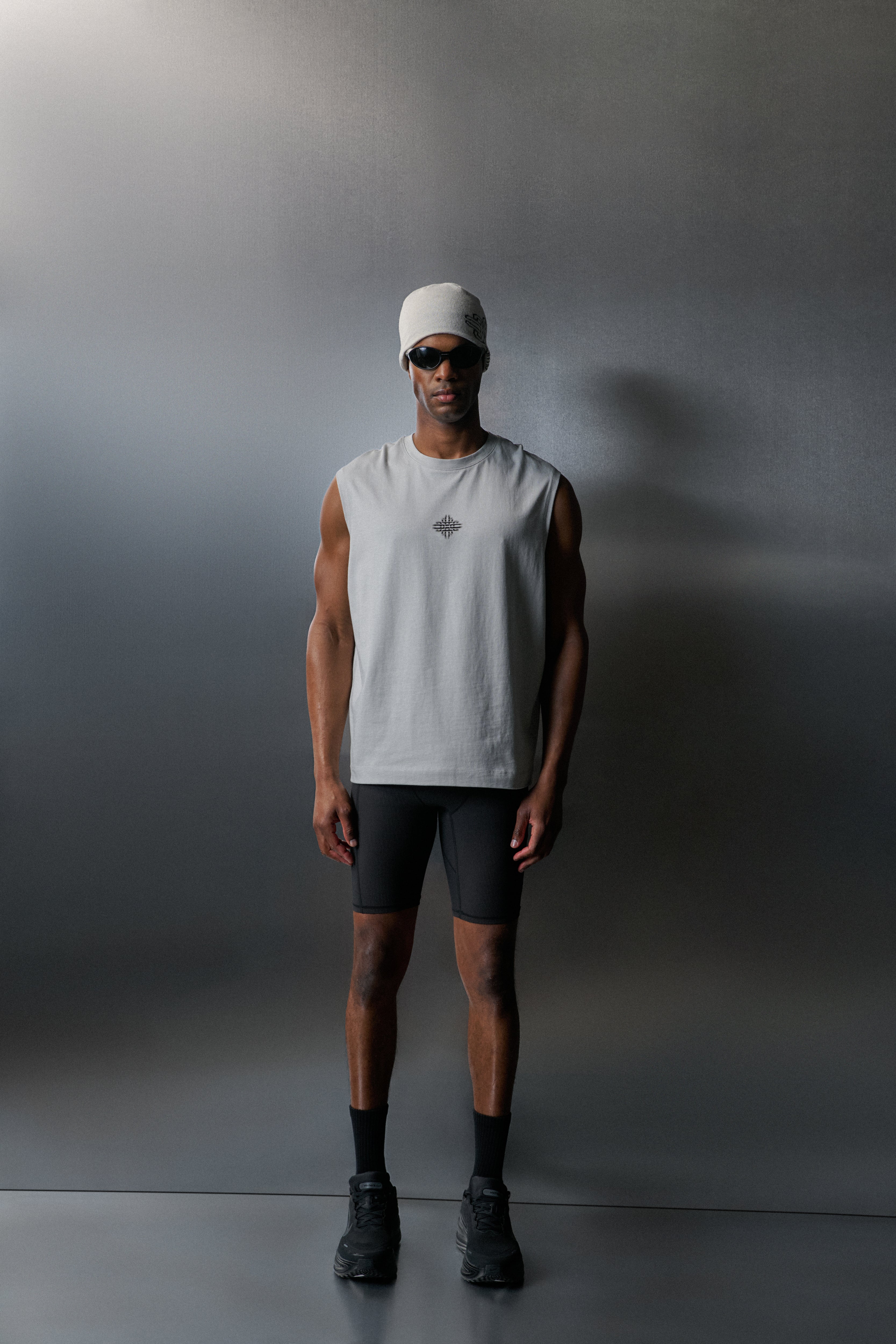 Person wearing a vest and shorts against a grey background