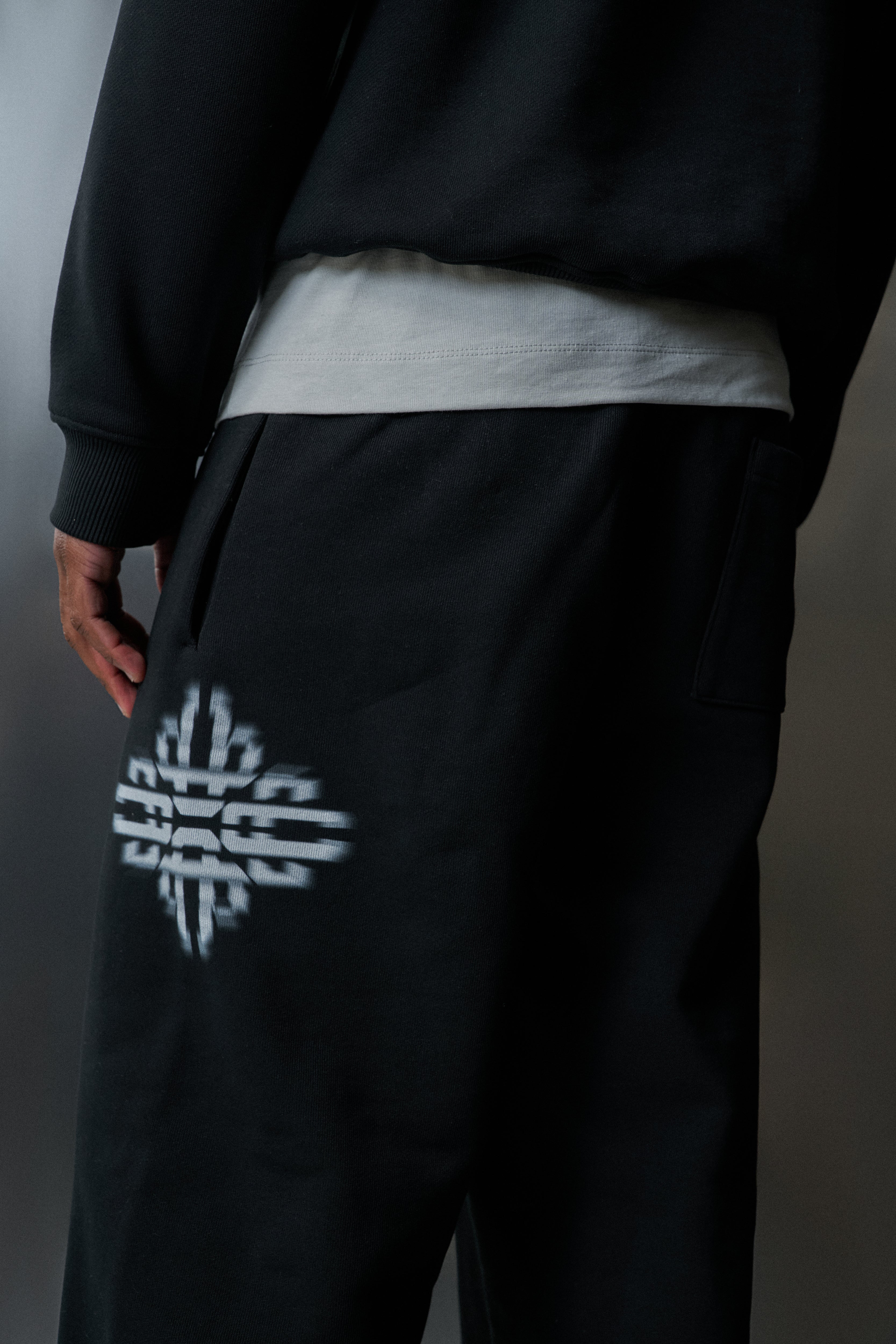 Black joggers with a white logo on a grey background