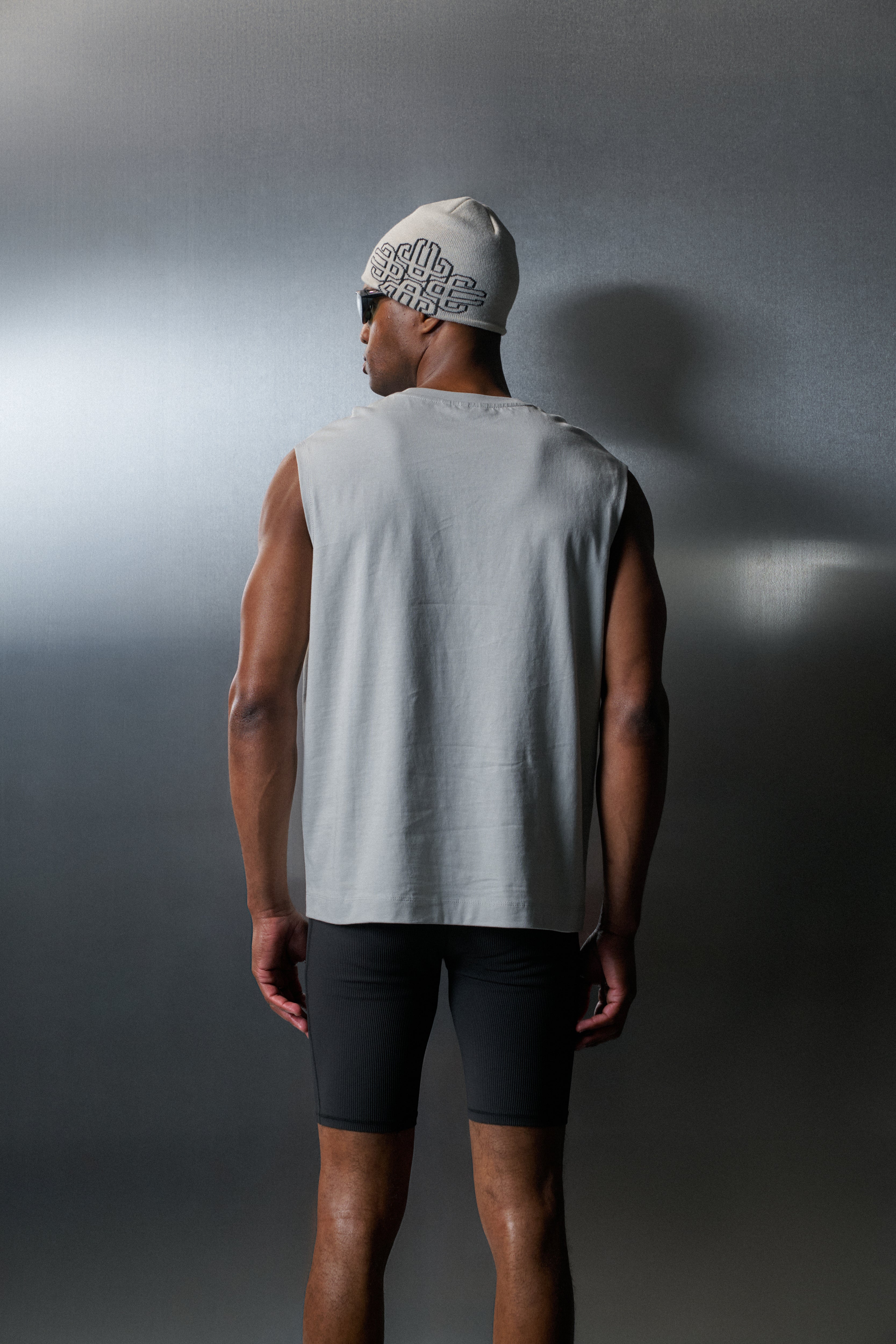 Man wearing a vest and cap against a grey background