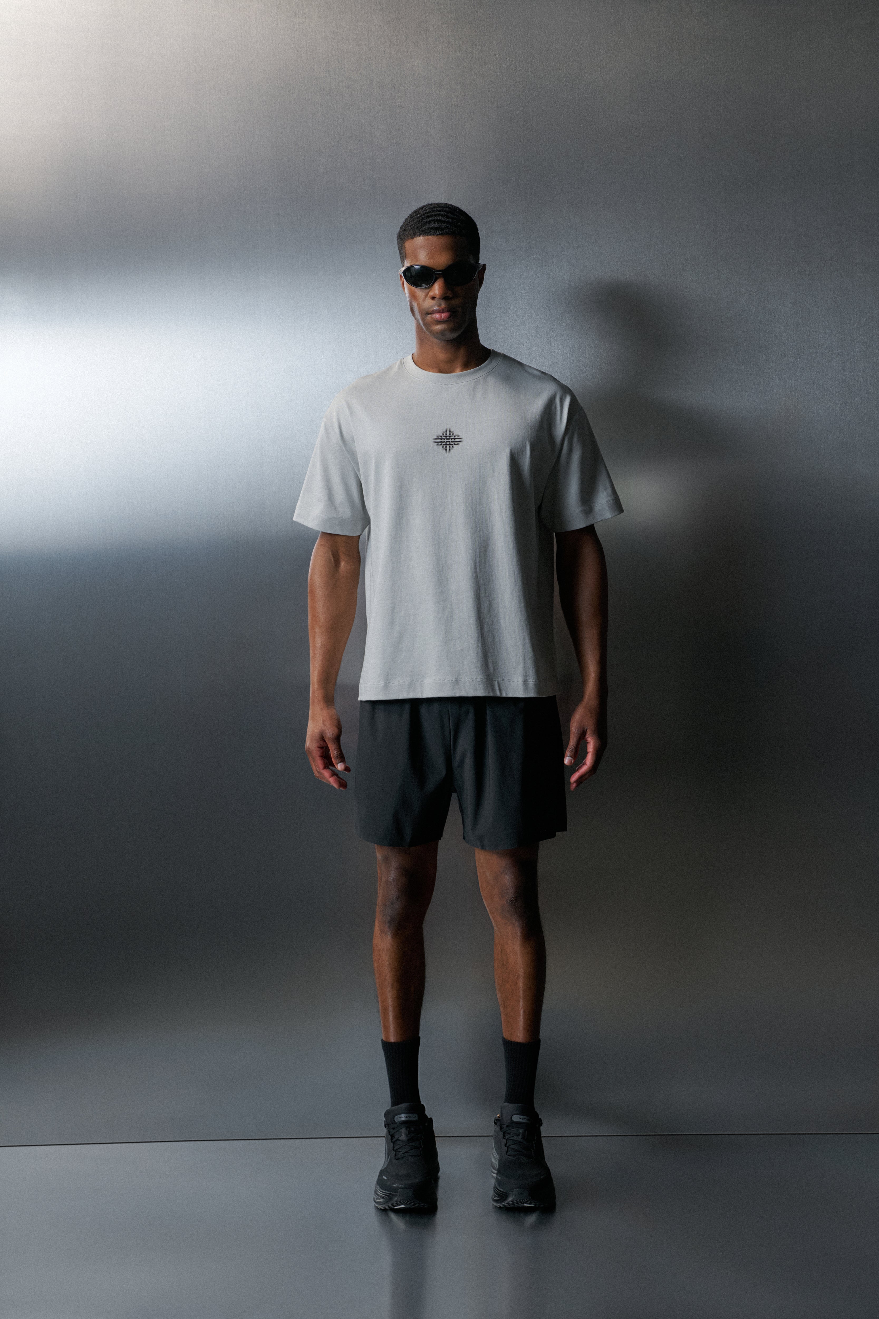 Man wearing a white t-shirt and dark shorts against a grey background