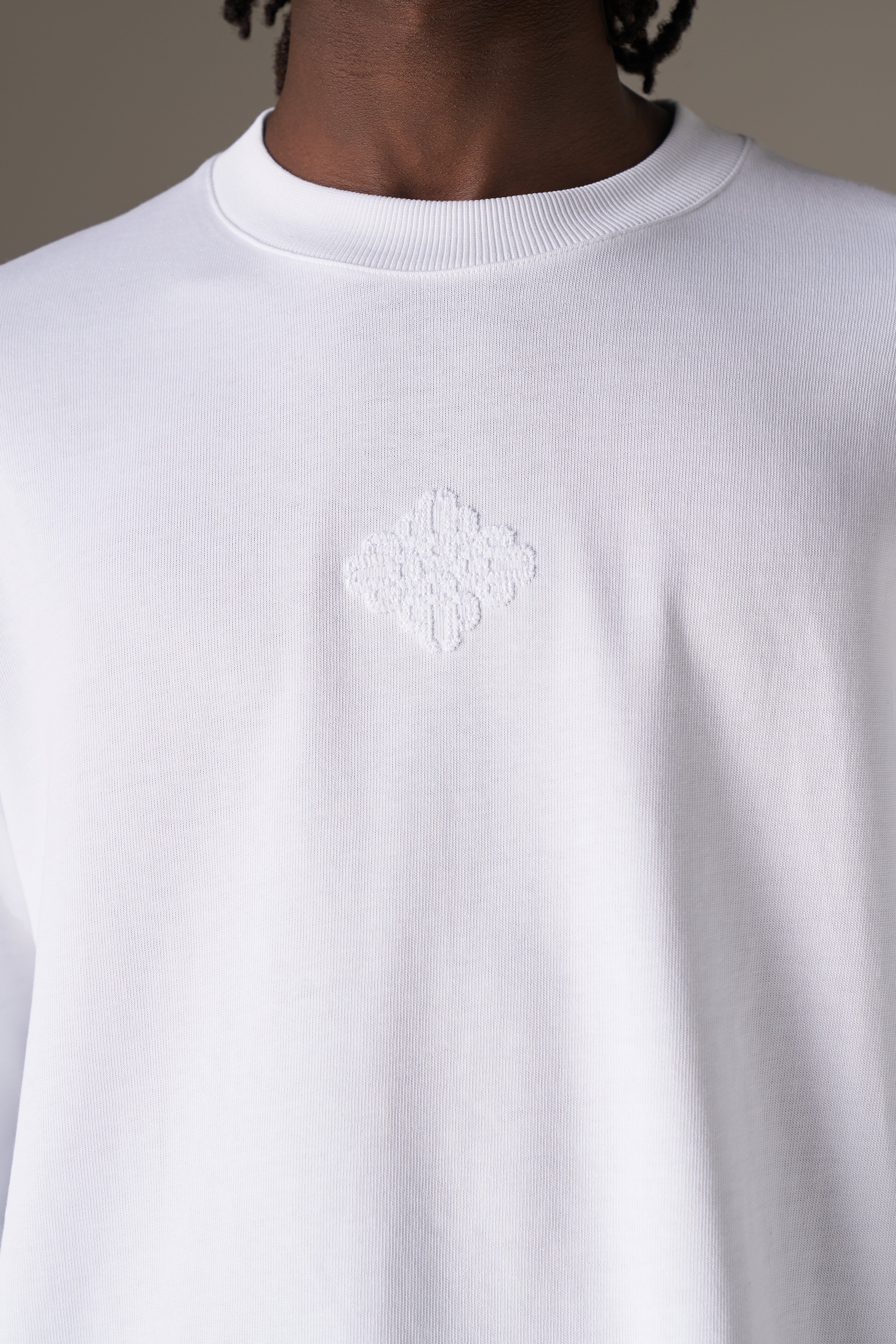 White long sleeve t-shirt with a logo on the chest against a neutral background