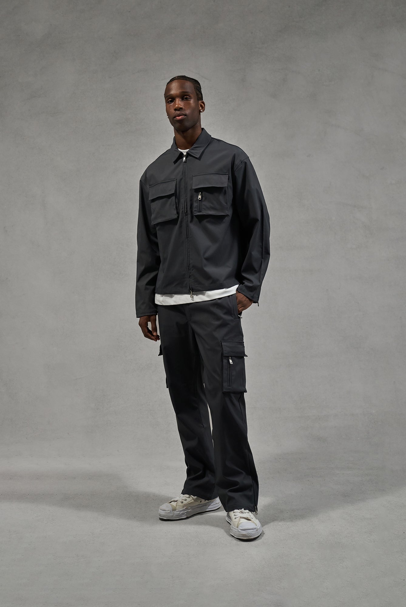 A man wearing a long sleeve grey shirt and matching pants against a plain background.