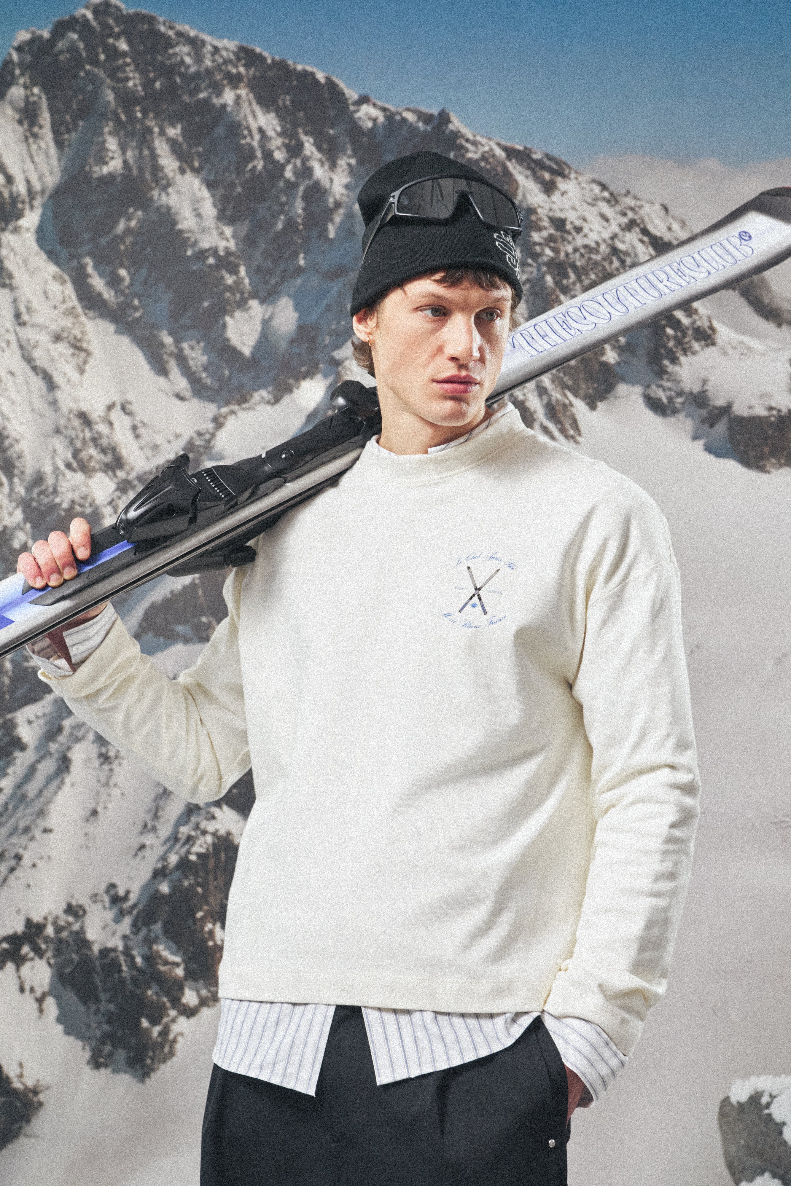 Person holding skis against a snowy mountain background