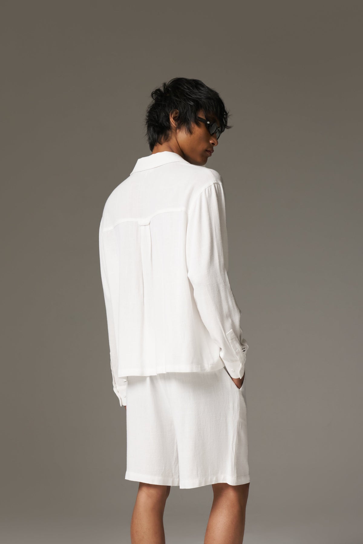 Person wearing a white outfit against a grey background