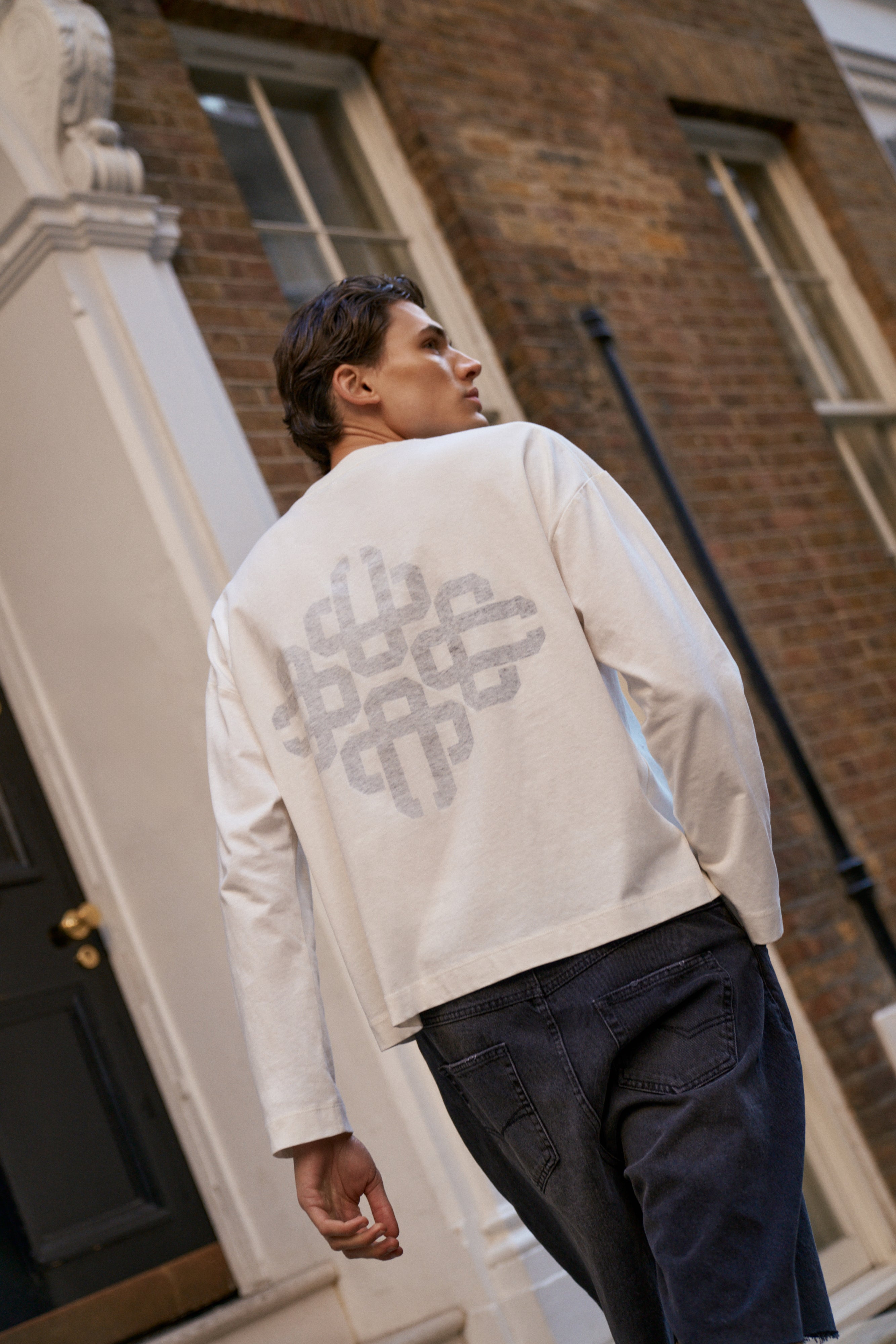Man wearing a white t-shirt with a geometric pattern in an urban setting