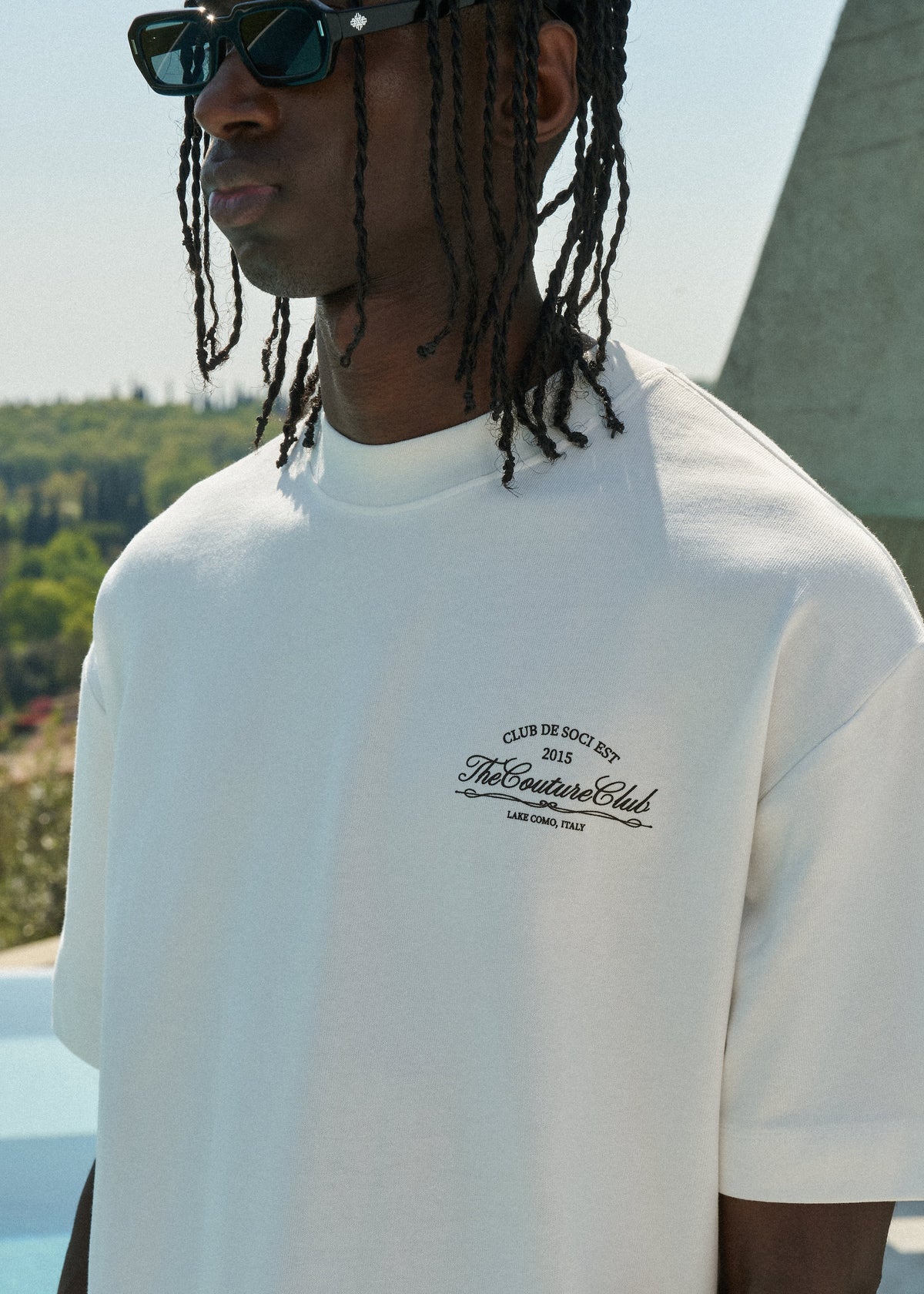 Person wearing a white t-shirt with a logo outdoors