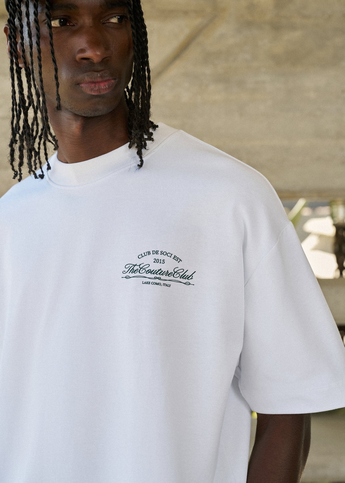 Person wearing a white t-shirt with text, standing outdoors.