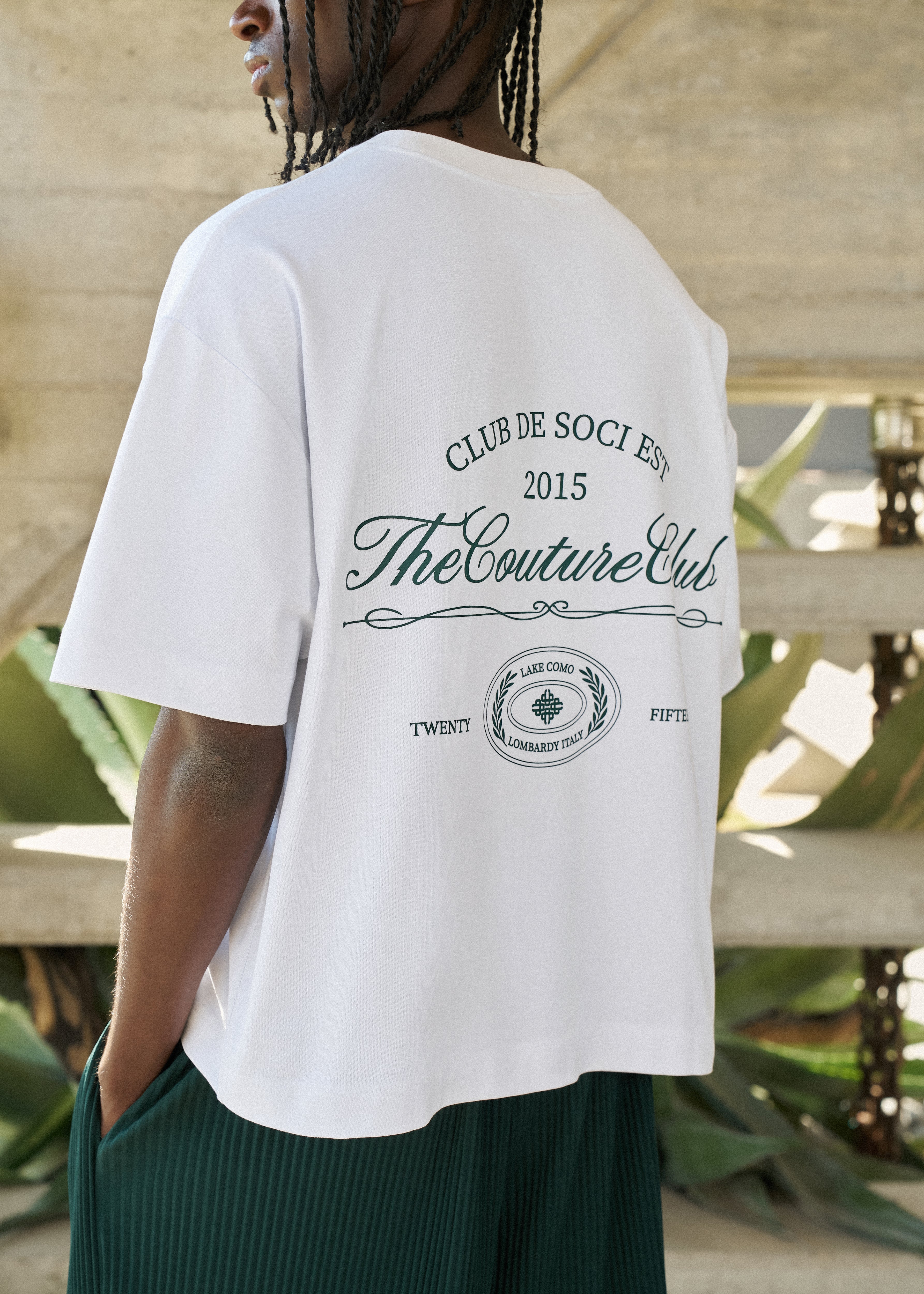 Person wearing a white t-shirt with 'The Couture Club' text and logo.