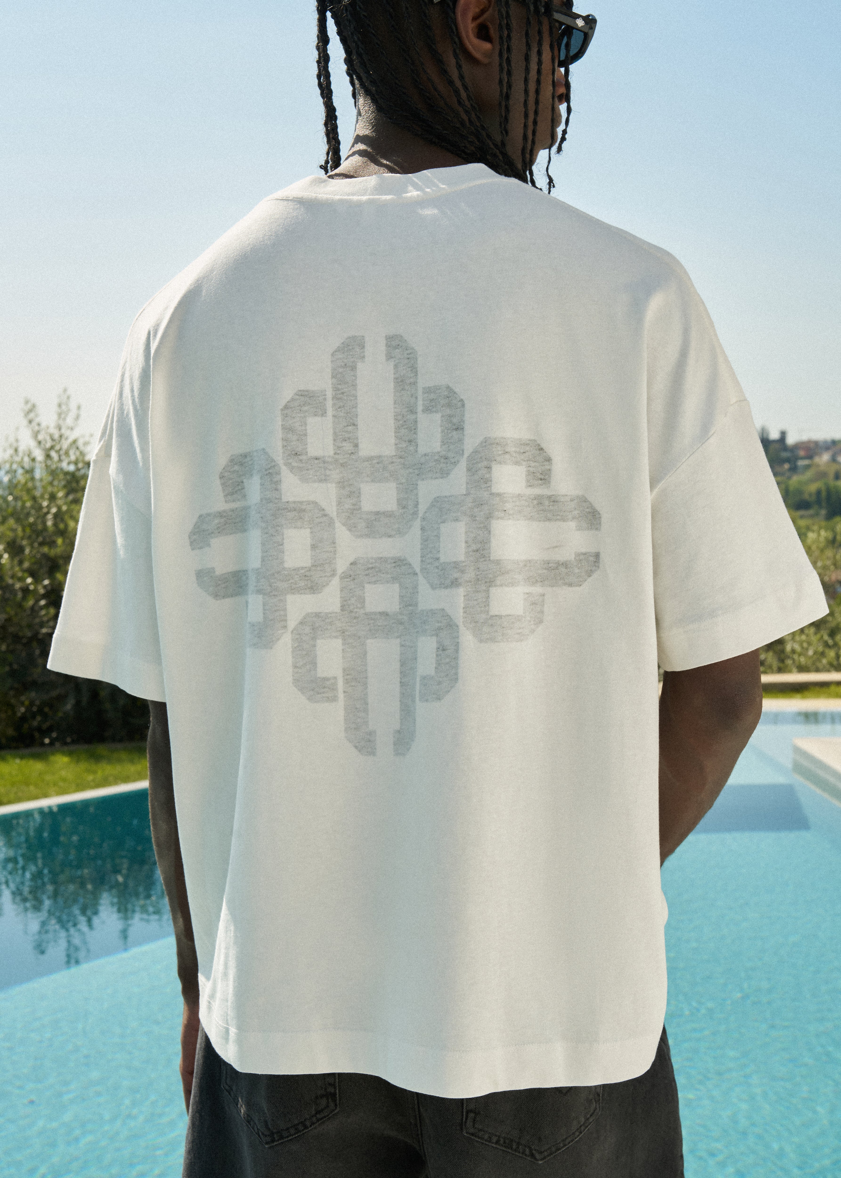 Person wearing a white t-shirt with a geometric design on the back.