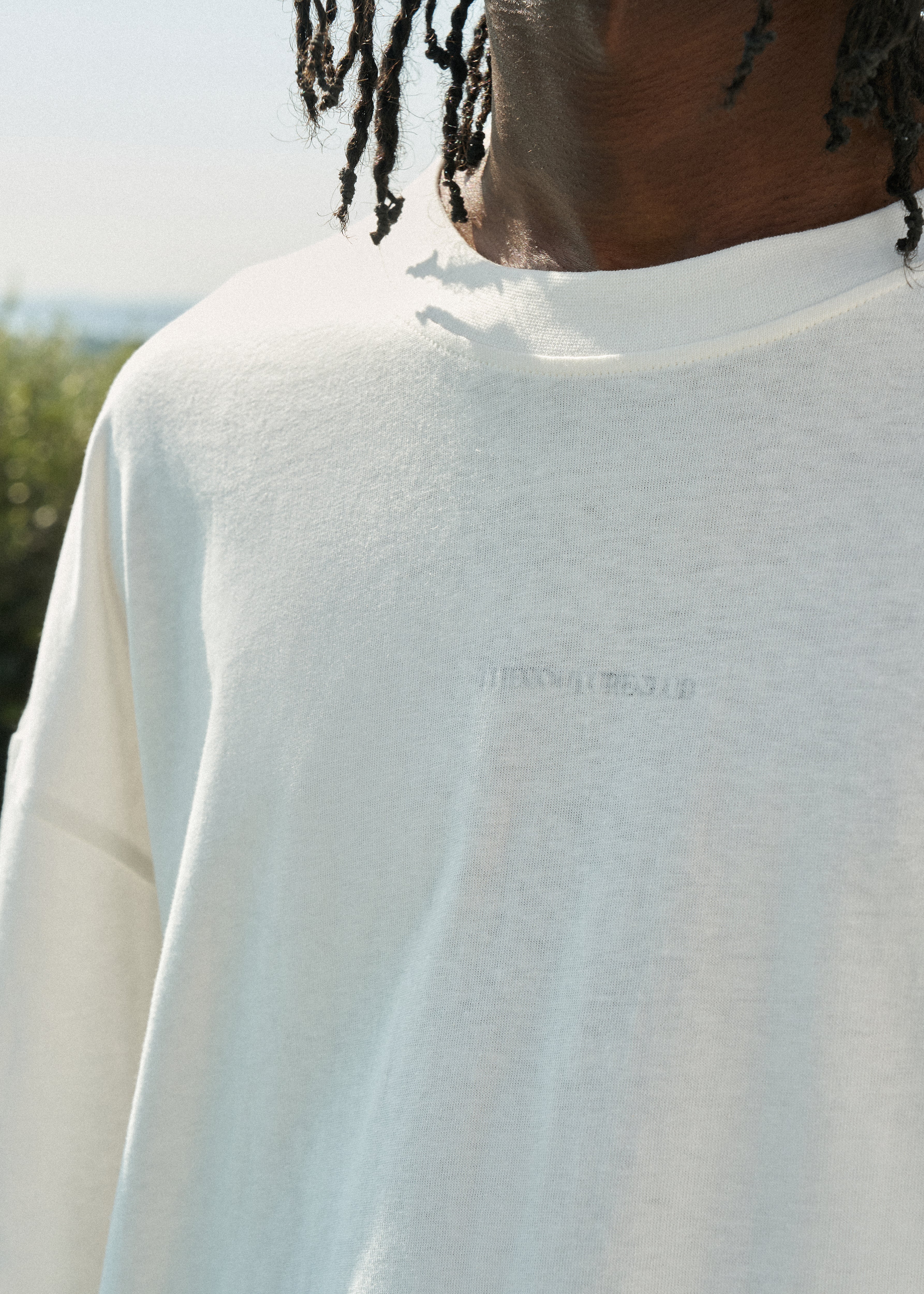 Close-up of a person wearing a white sweatshirt with a brand logo.