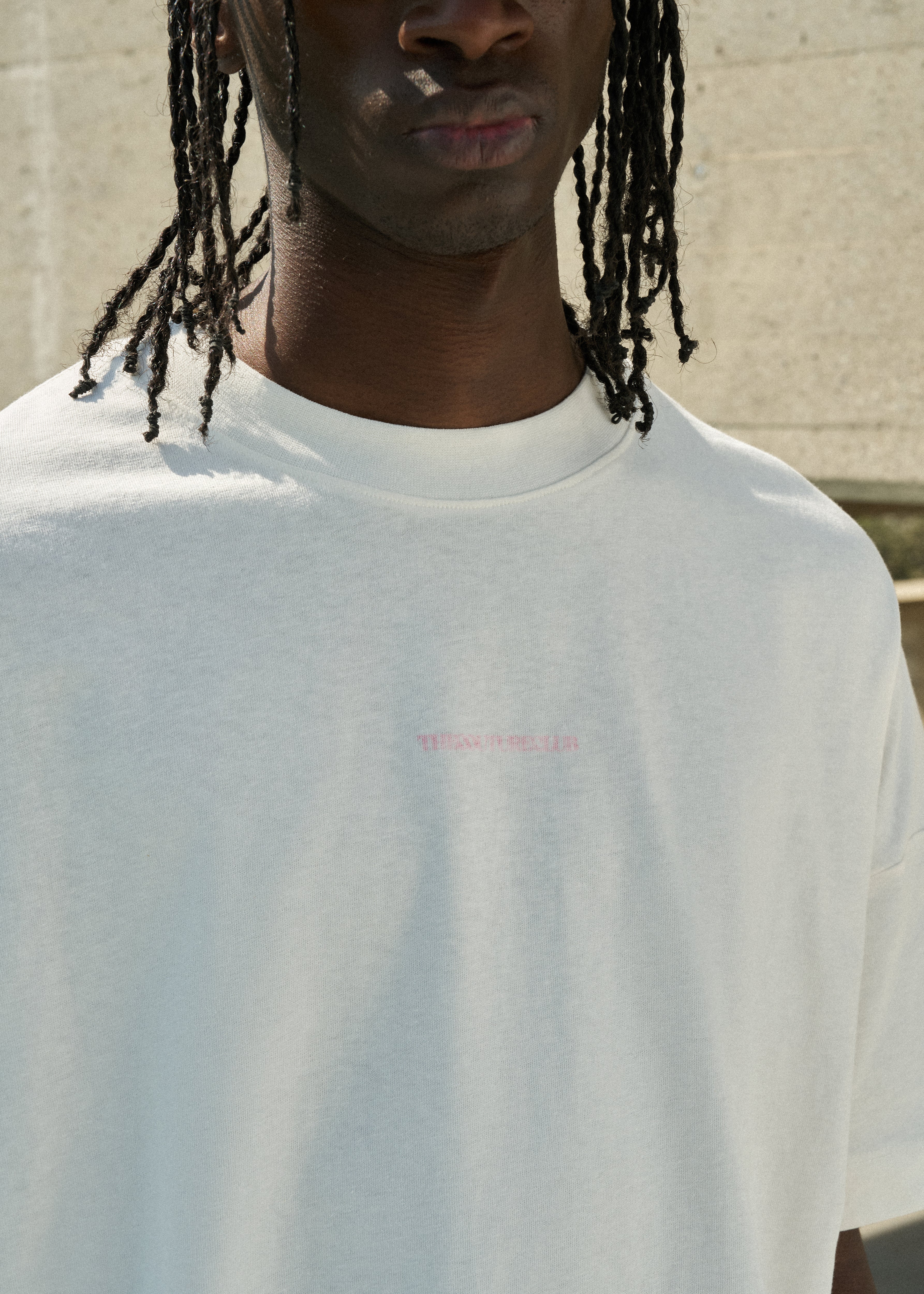 Person wearing a white t-shirt with a small pink logo