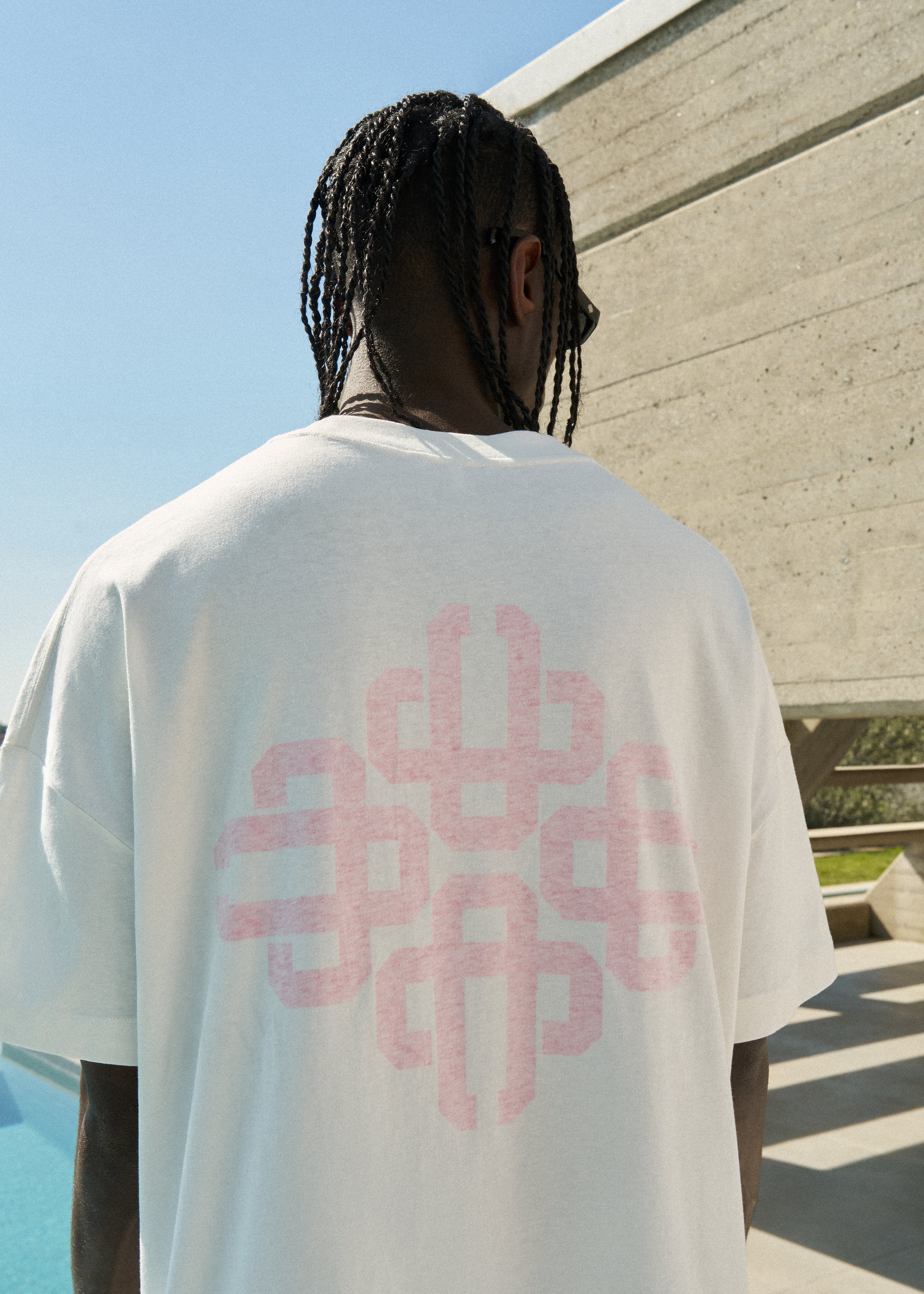 Person wearing a white t-shirt with pink graphic on the back of the t-shirt