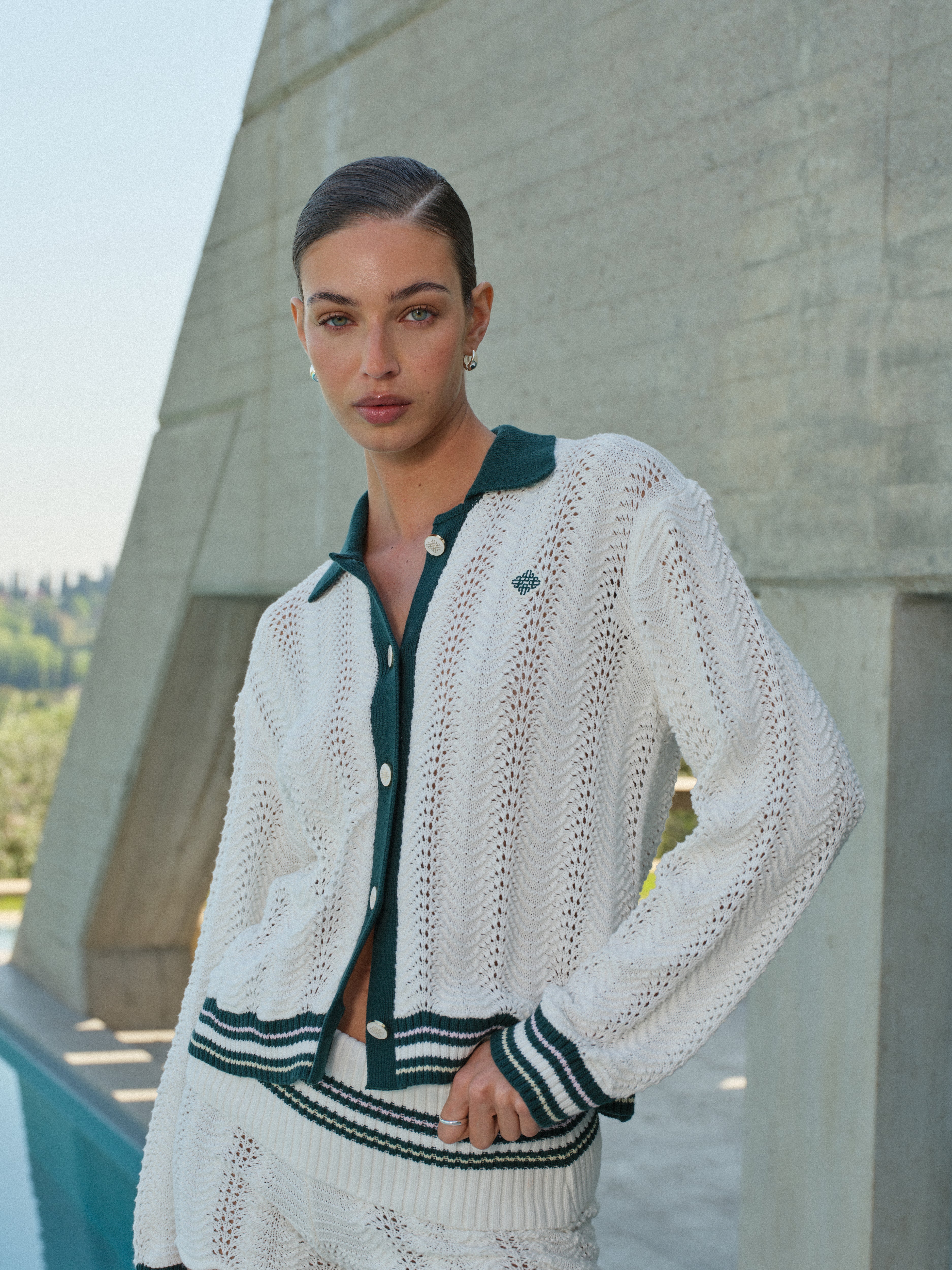 Woman wearing a white knit cardigan with green.